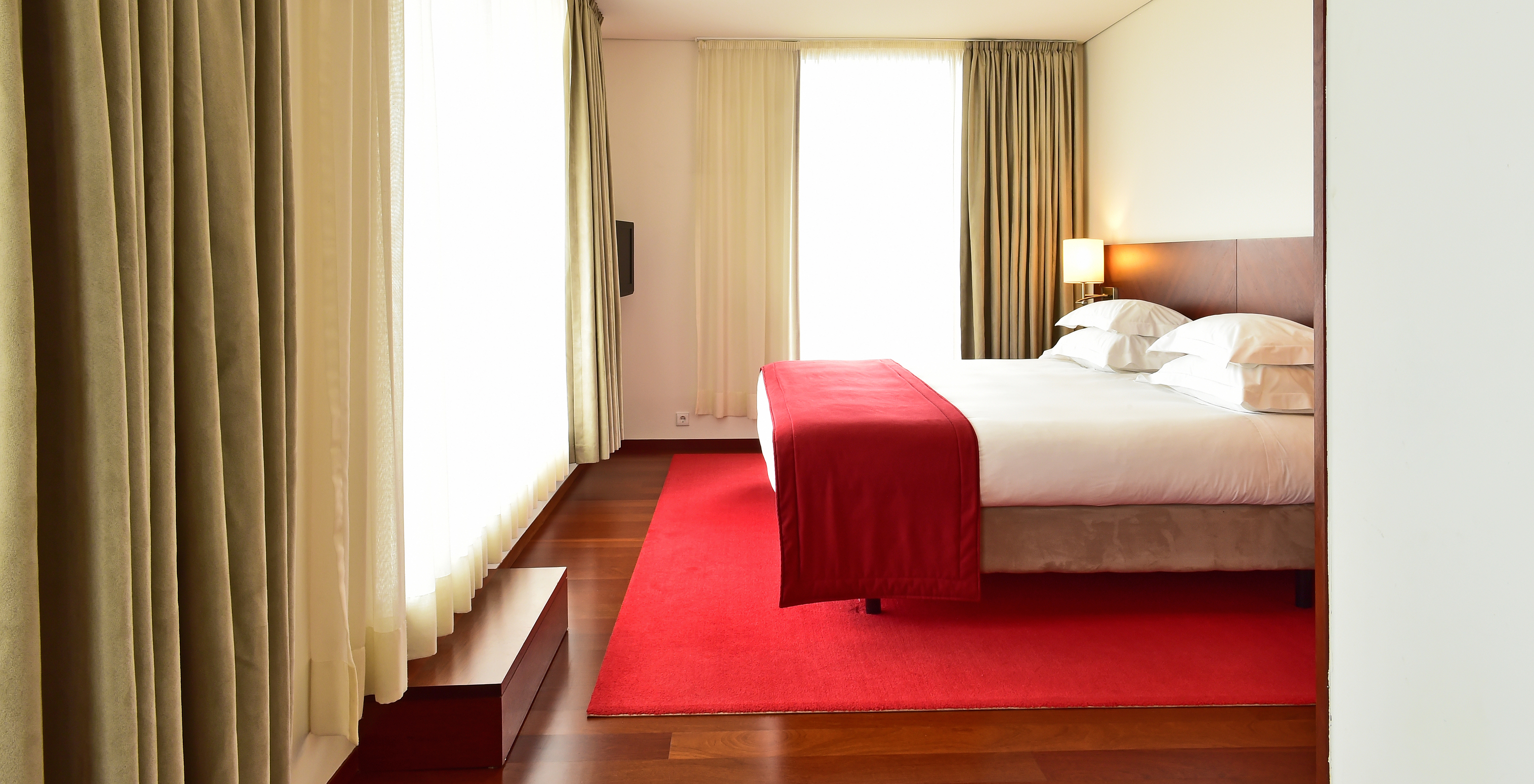 The Special Suite of the Pousada Viseu has a double bed, a lamp and two large windows with curtains