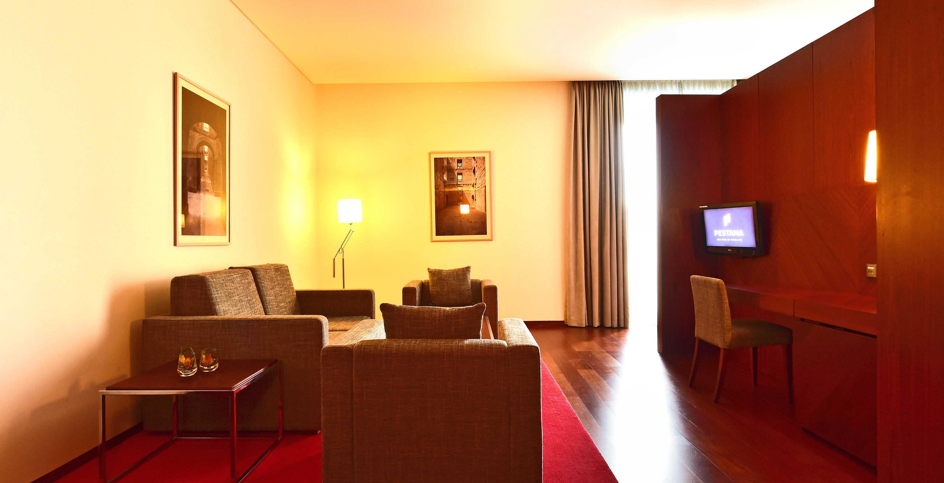 The Standard Suite of the Pousada Viseu has a sofa, two armchairs, a desk with chair, and a television