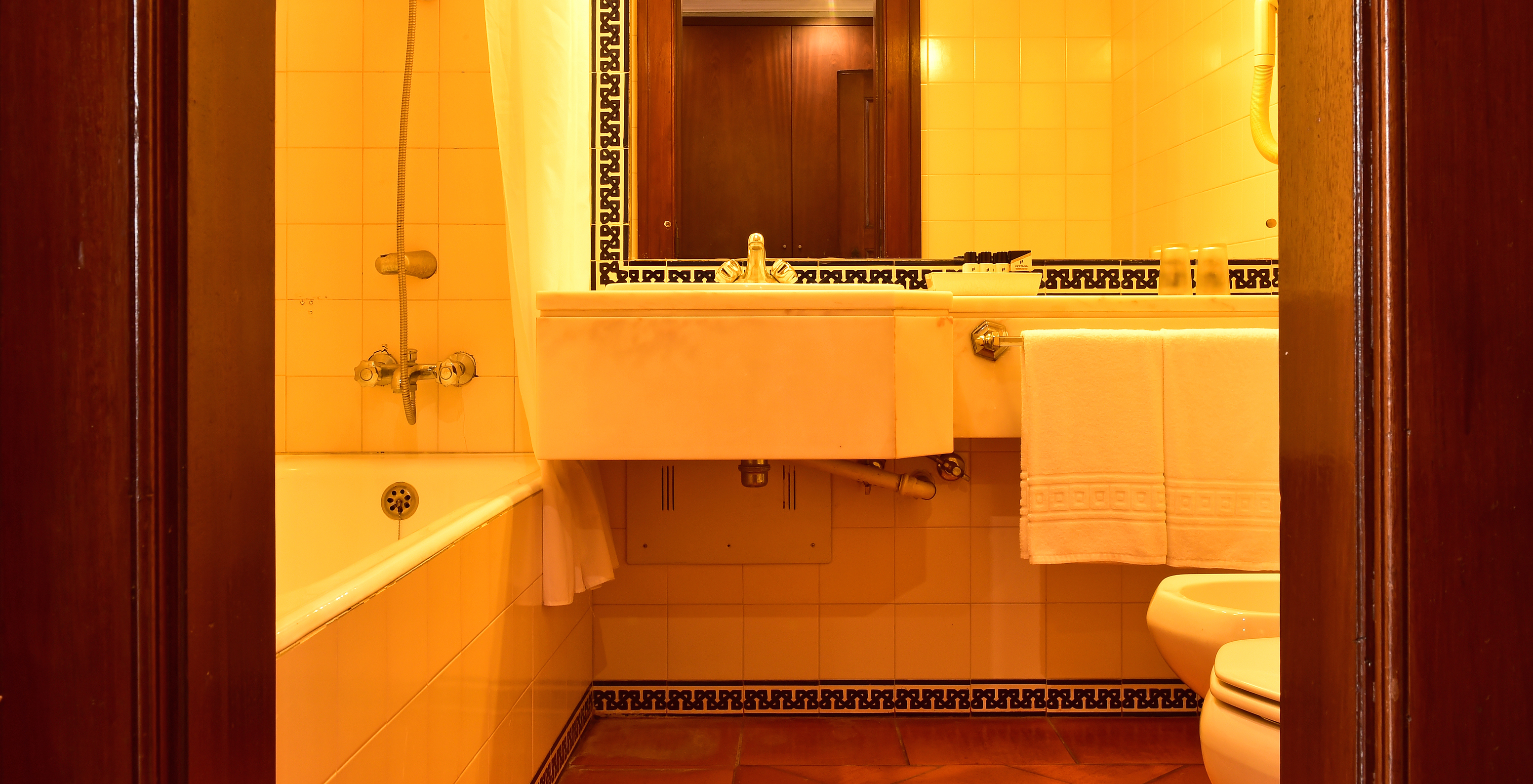 The Classic Room at Pousada Castelo Palmela has a bathroom with sink with mirror, bathtub, and tiles on the wall