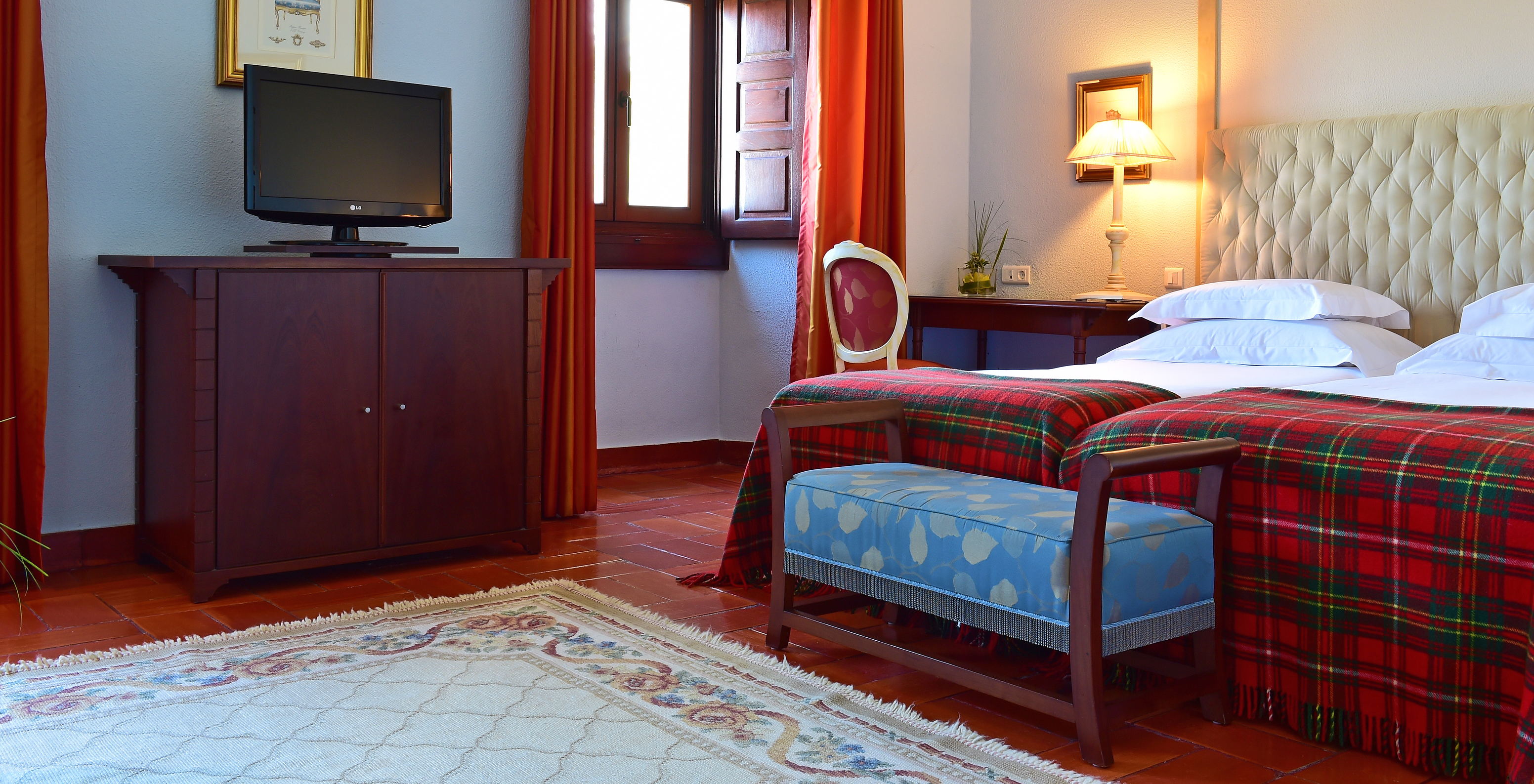 The Classic Room at Pousada Castelo Palmela has two beds and a bench at the end of the bed, a television, and a window