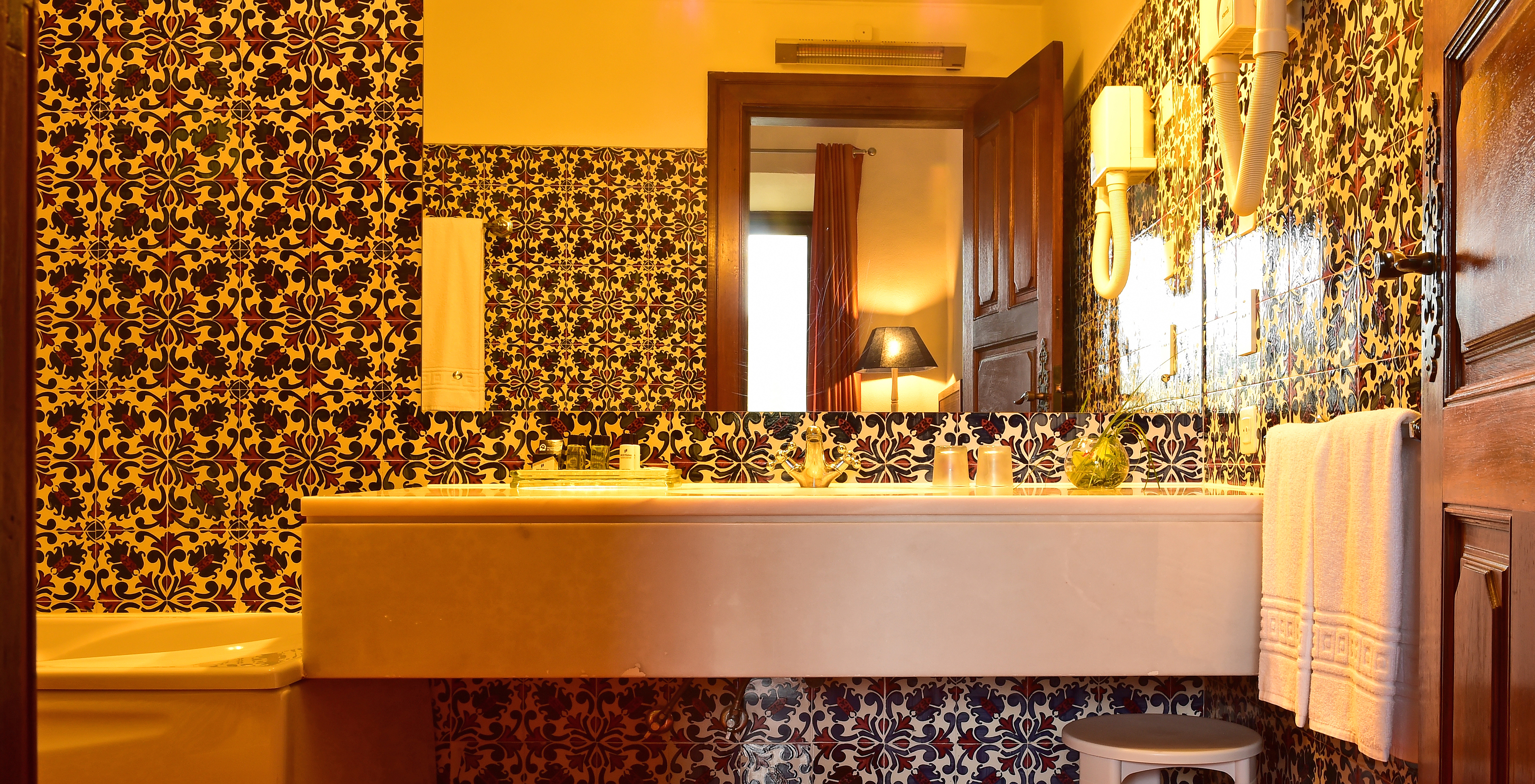 The Master Suite at Pousada Castelo Palmela has a bathroom with sink with mirror, towels, and a small bench