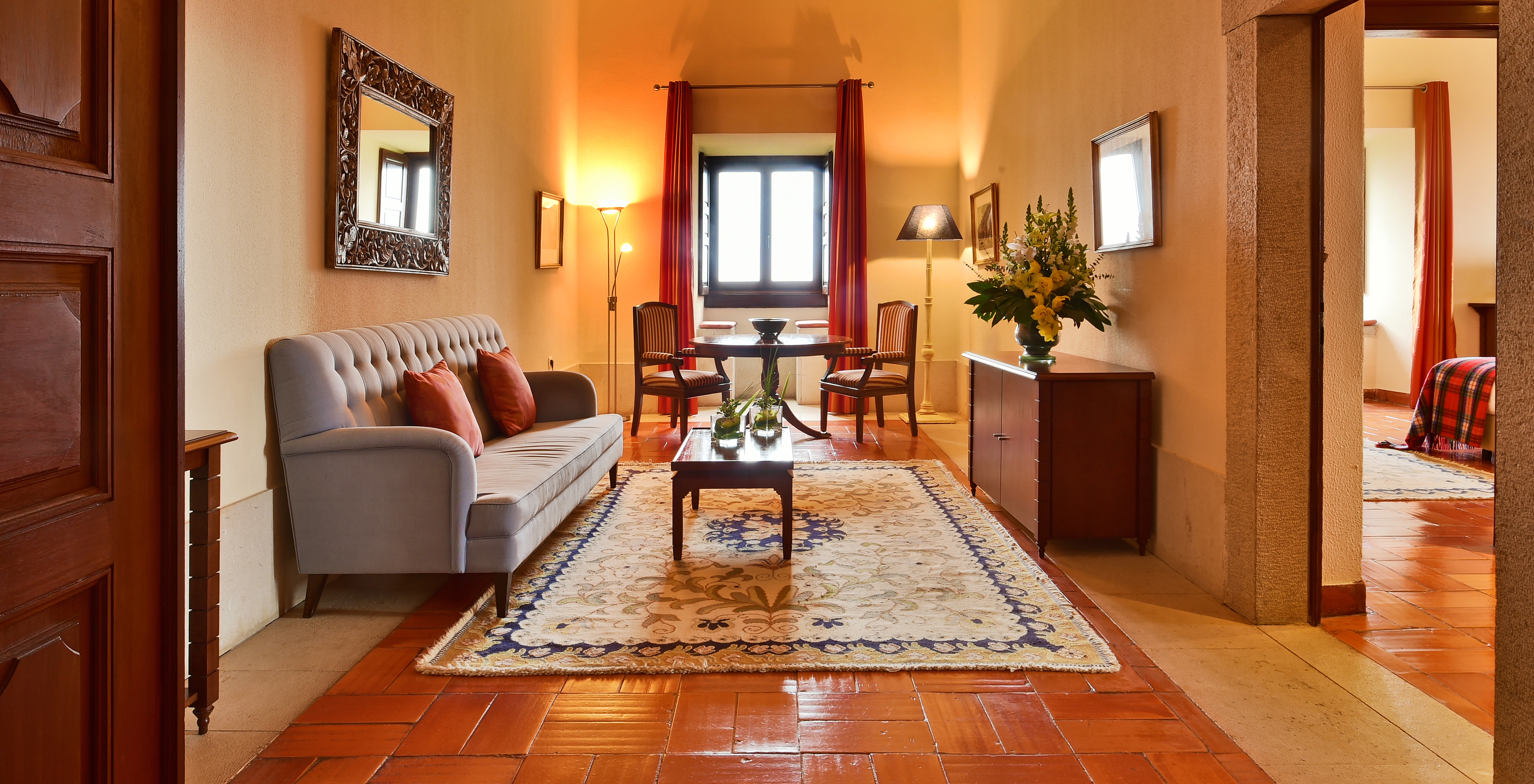 The Special Suite at Pousada Castelo Palmela has a living room with sofa, wooden furniture with a vase of flowers and a table