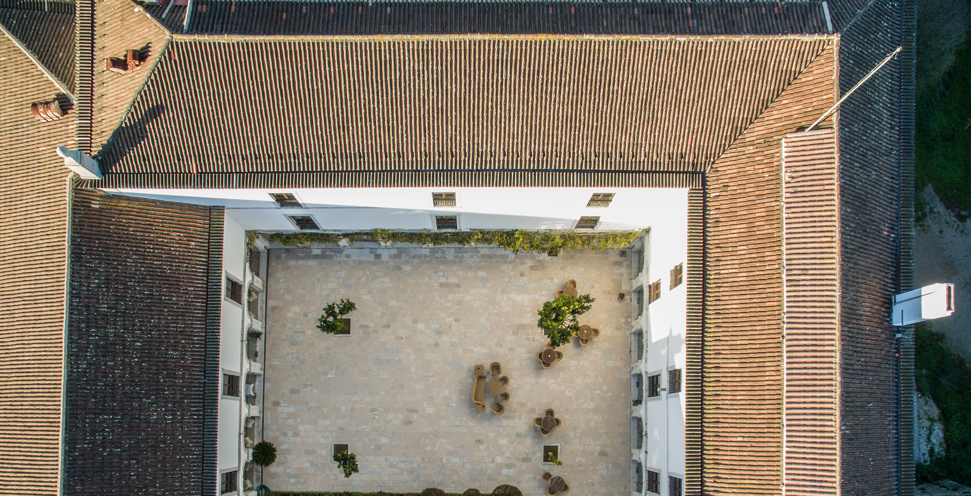 Aerial view of the cloister at Pousada Castelo Palmela, with trees, sofas, tables, and chairs