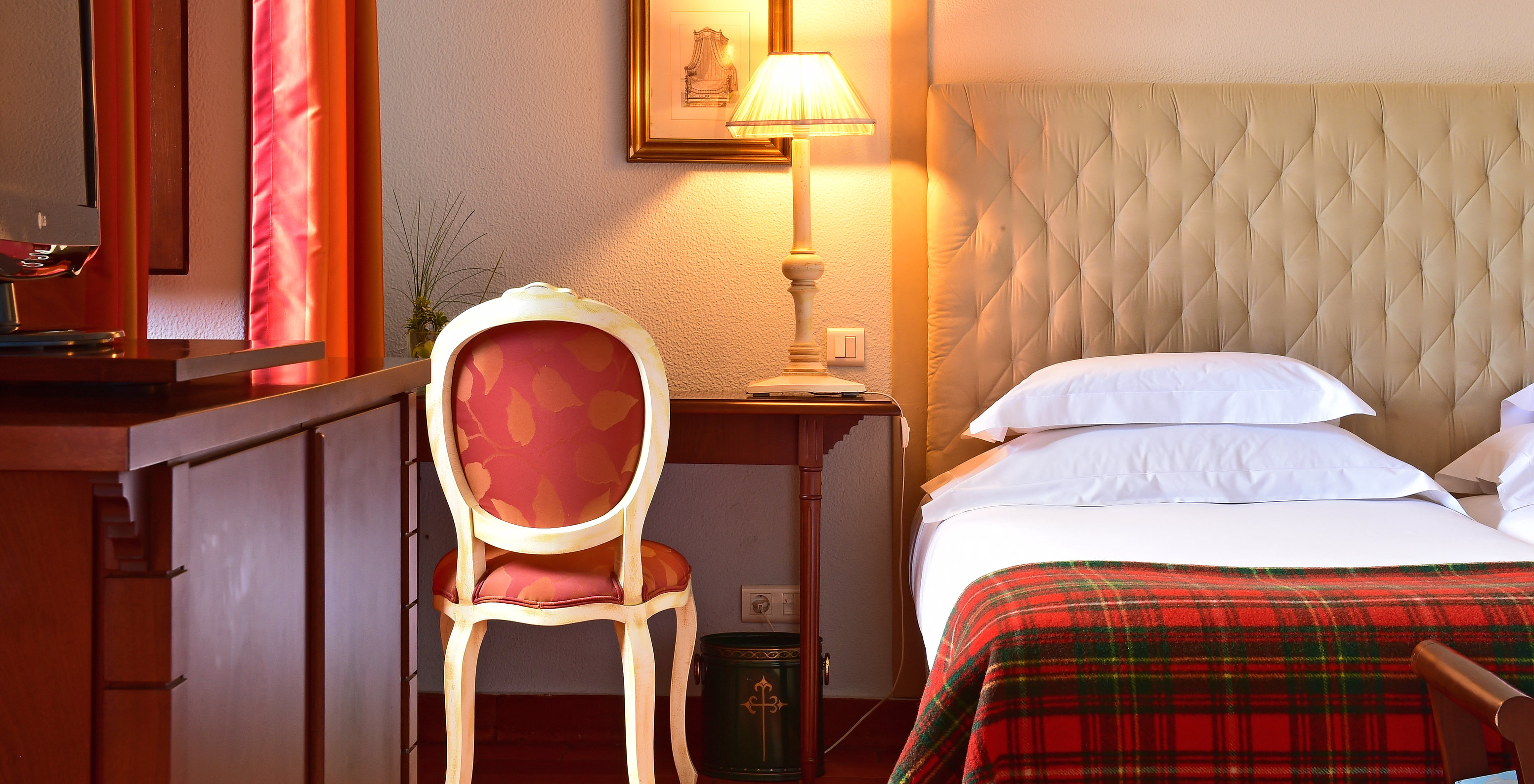 The Superior Family Room at Pousada Castelo Palmela has a bed with white sheets and checkered blanket, and a wooden desk