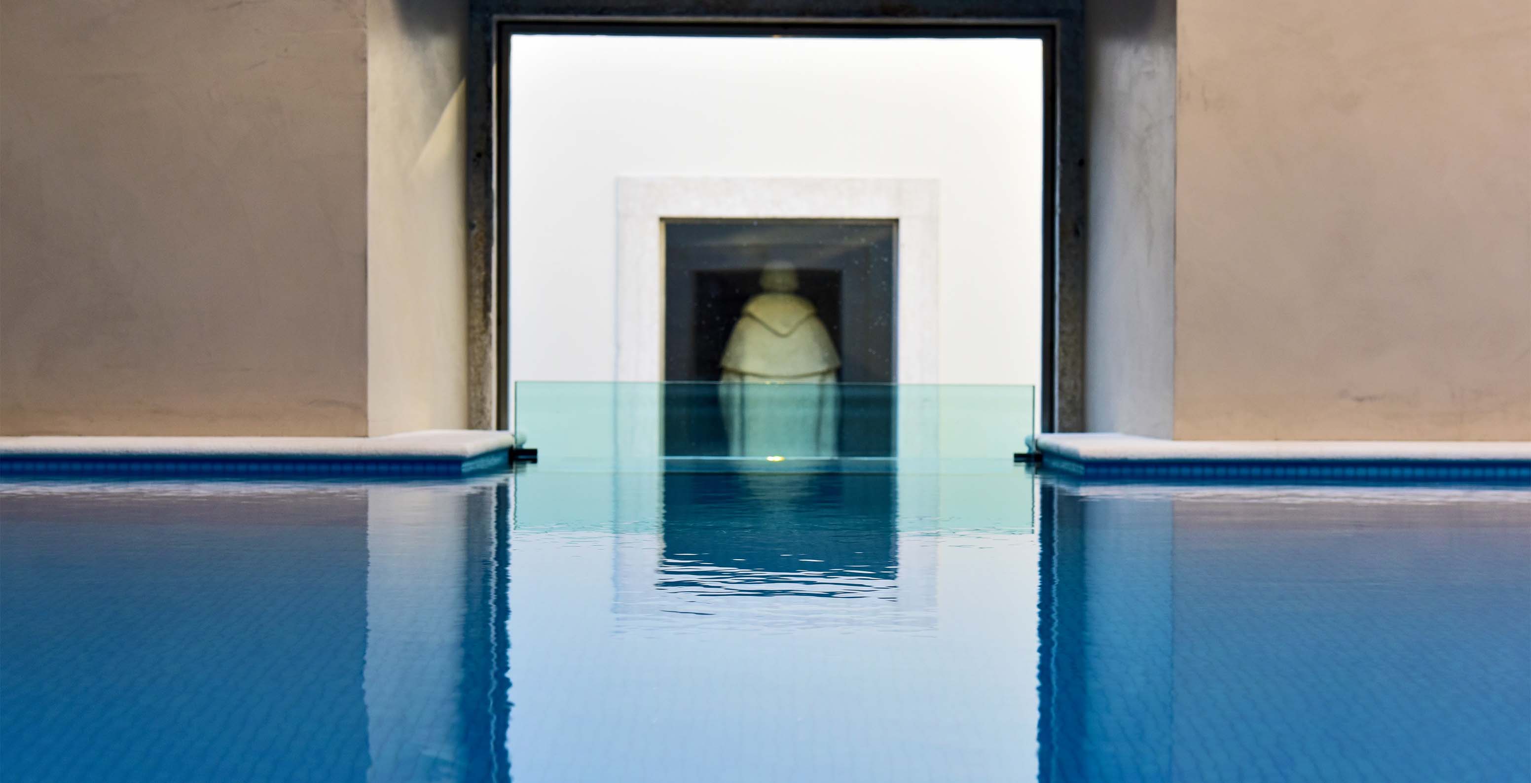 Indoor pool of the Pousada Lisboa Praça do Comércio with a view of a statue