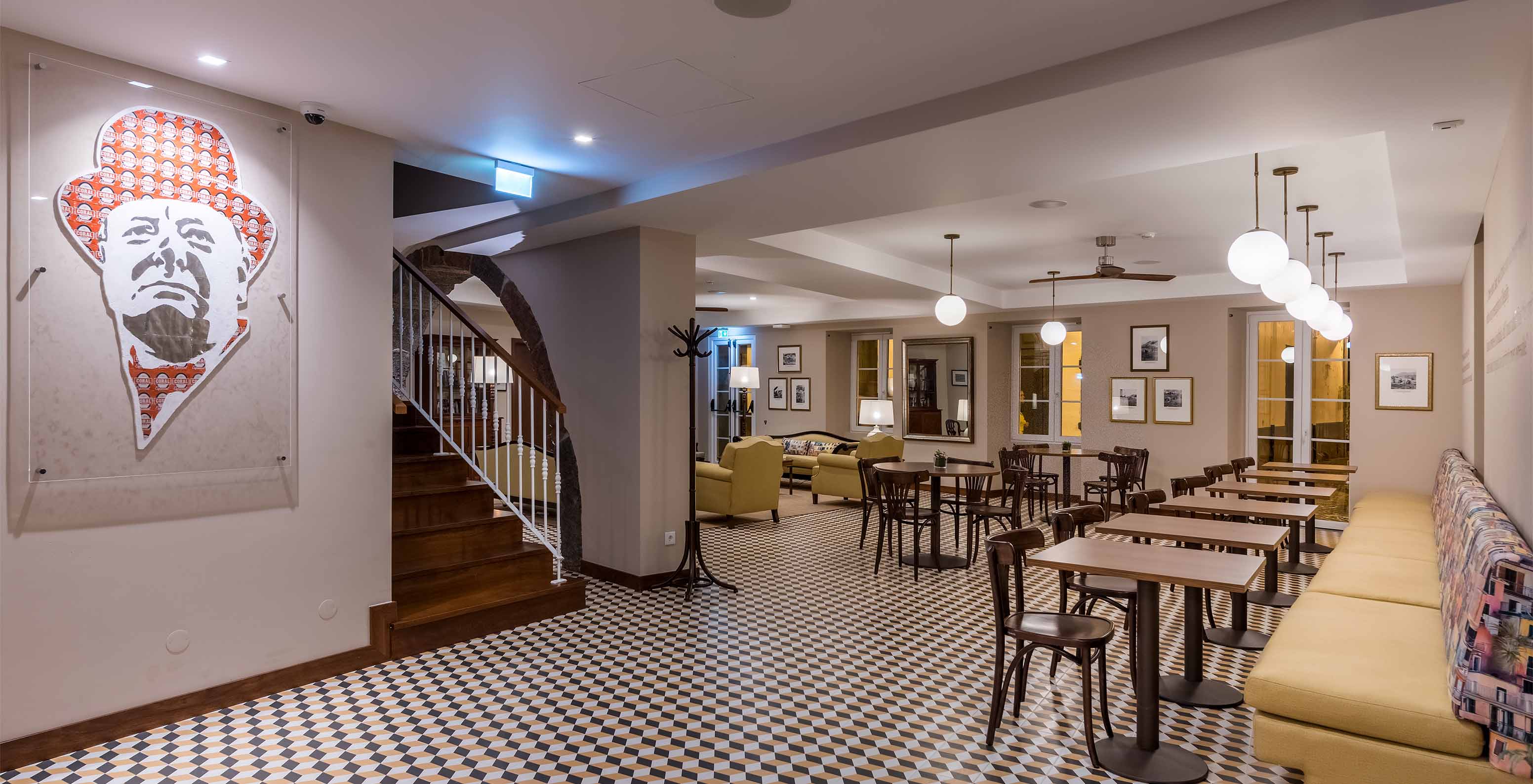 Hotel in Câmara de Lobos Bay, near Funchal, has a geometric patterned floor and yellow sofas with tables and chairs