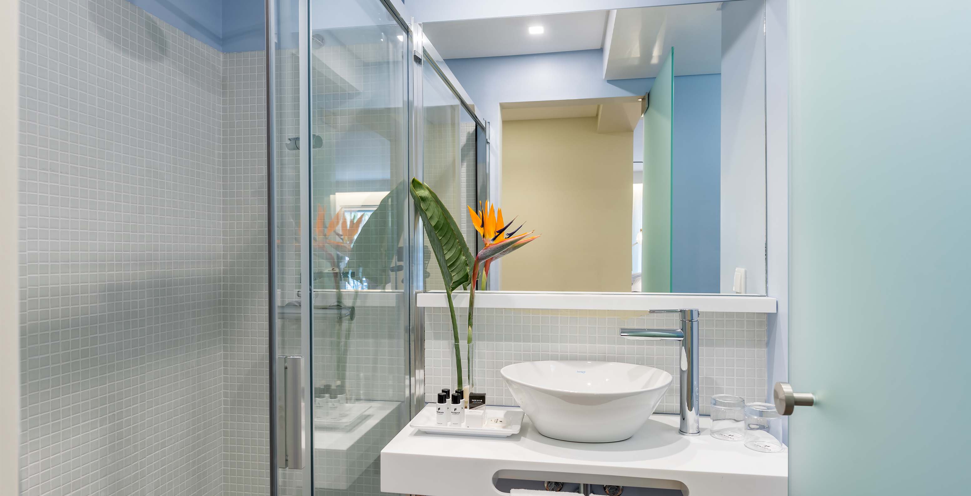 The Deluxe Bay View Room at Pestana Churchill Bay has a blue bathroom with amenities, a sink, and a shower