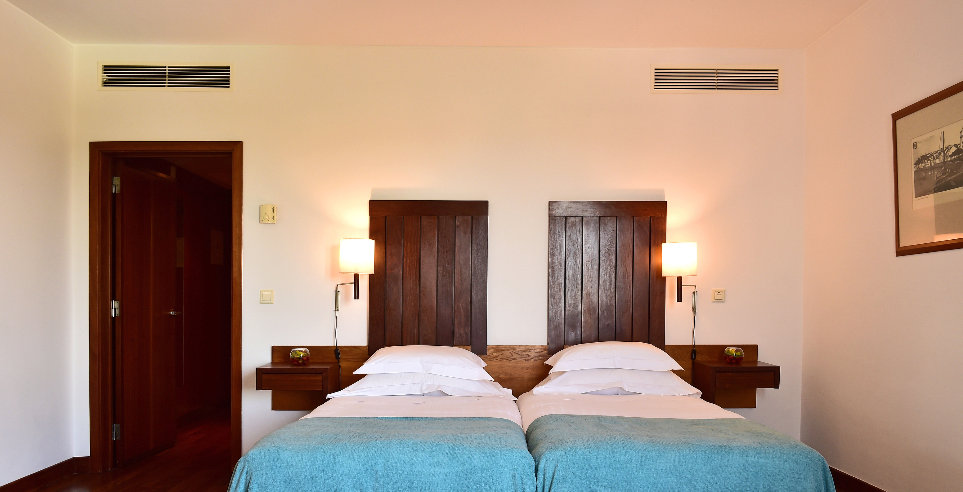 The Classic Room of the Pousada Castelo Alcácer do Sal has two separate beds, with a blue blanket and a wooden headboard