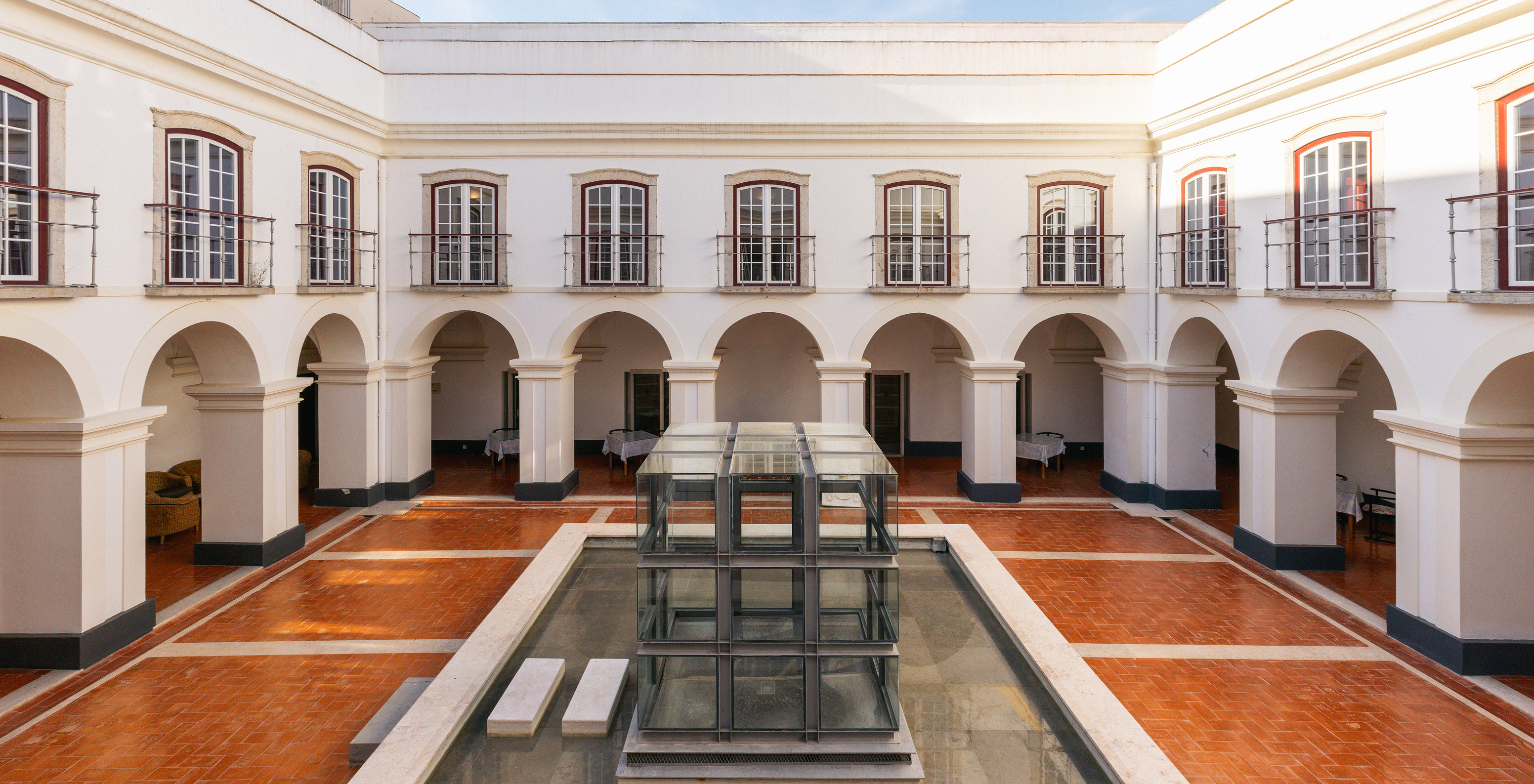 View of the cloisters at Pousada Castelo Alcácer do Sal, with arches, balconies, and a central fountain