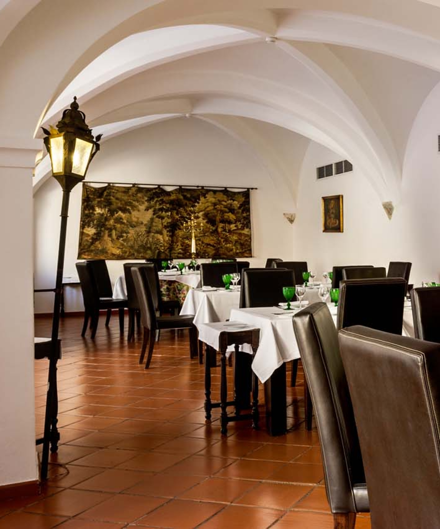 Restaurant with several set tables and a vaulted ceiling at Pousada Castelo Alvito, a hotel in Alvito with a spa