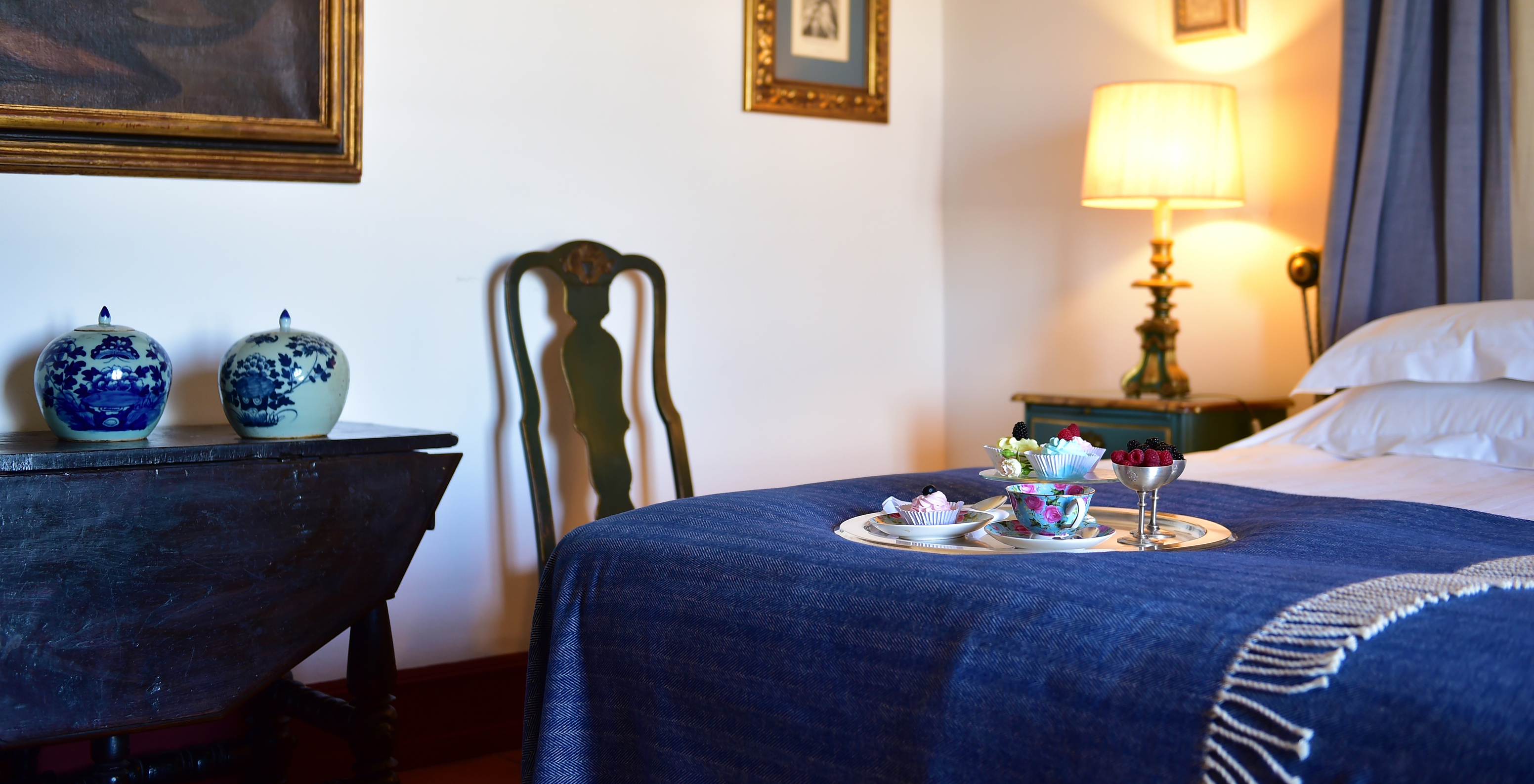 The Superior Room at Pousada Castelo Estremoz has a double bed with a snack on top consisting of tea, fruit, and sweets