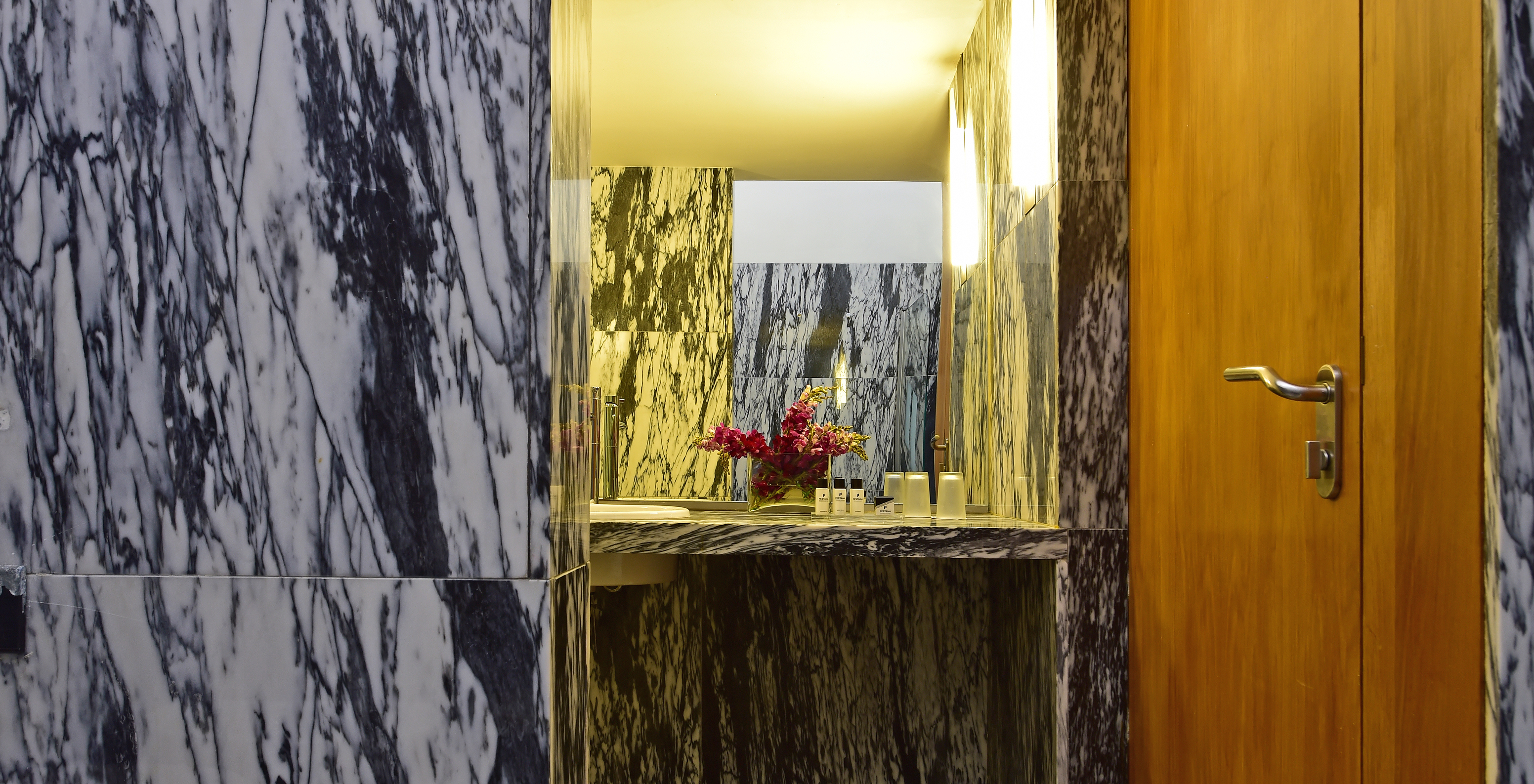 The Classic Room of The Pousada Convento Arraiolos has a marble bathroom with a sink and a vase of flowers