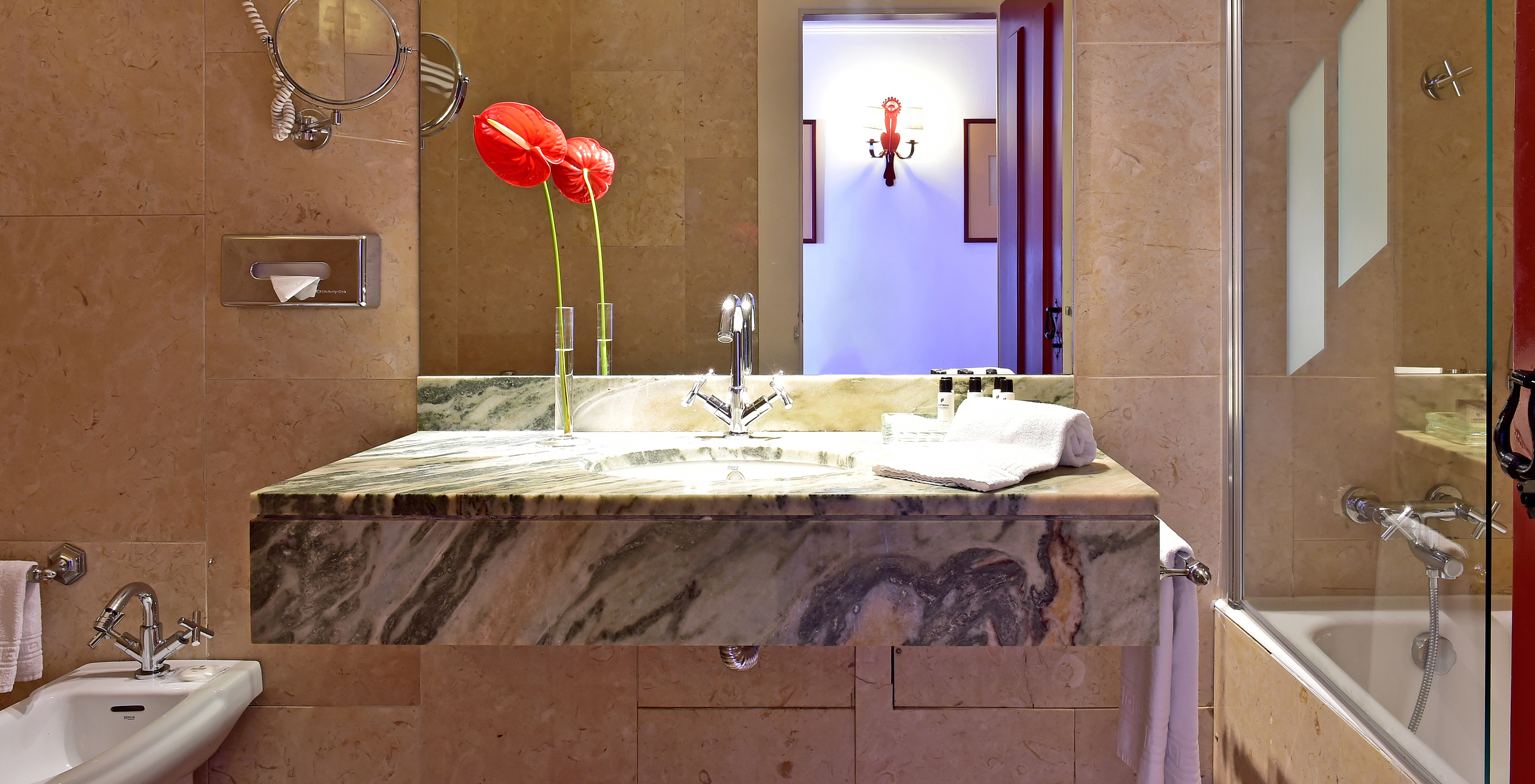 The Classic Room of The Pousada Convento Beja has a counter with a sink, a large mirror, and a decorative flower