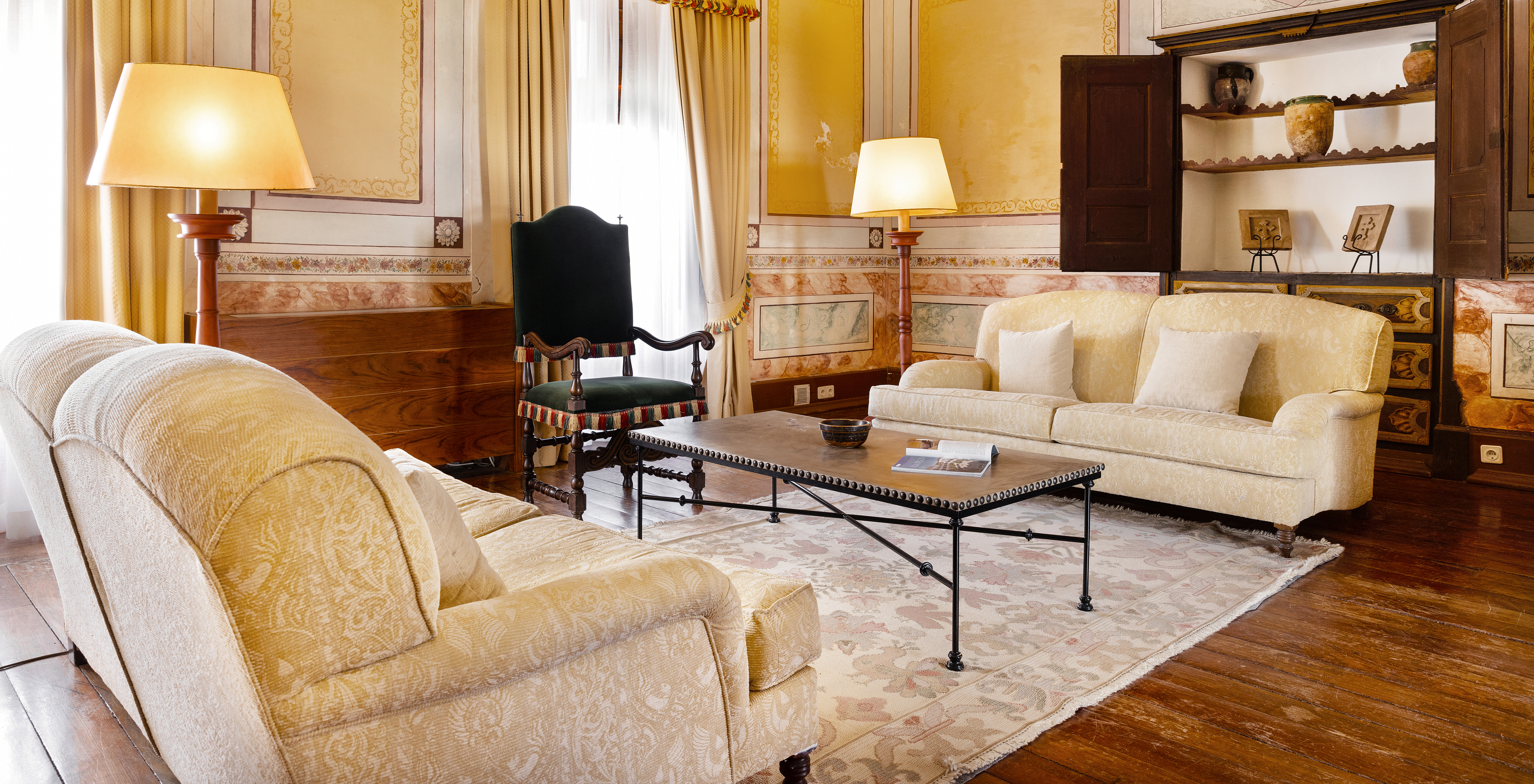 Living room at Pousada Convento Vila Viçosa, with two cream sofas and a side table and a decorative cabinet