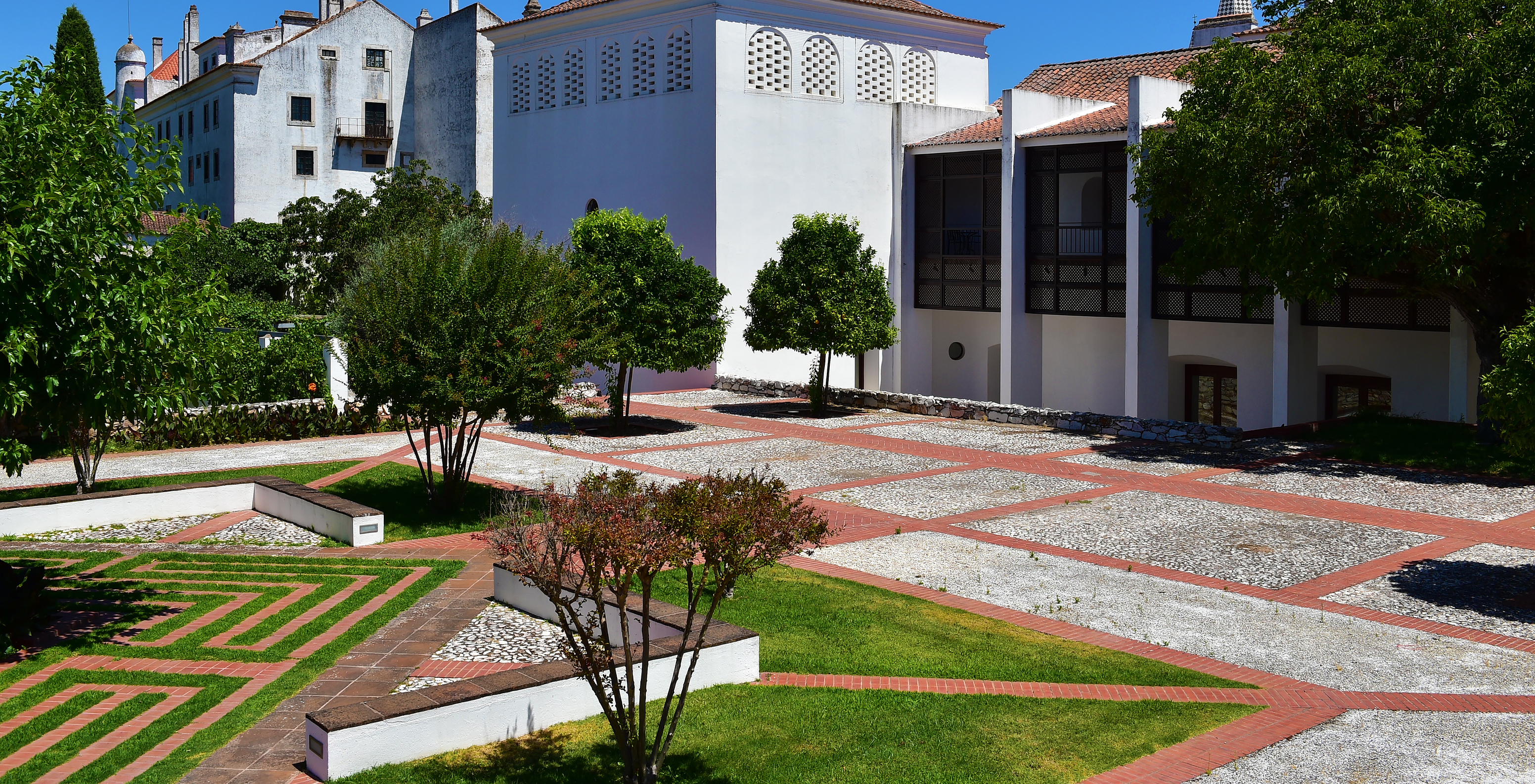 Courtyard of Pousada Convento Vila Viçosa with tiled floors, benches, and grass