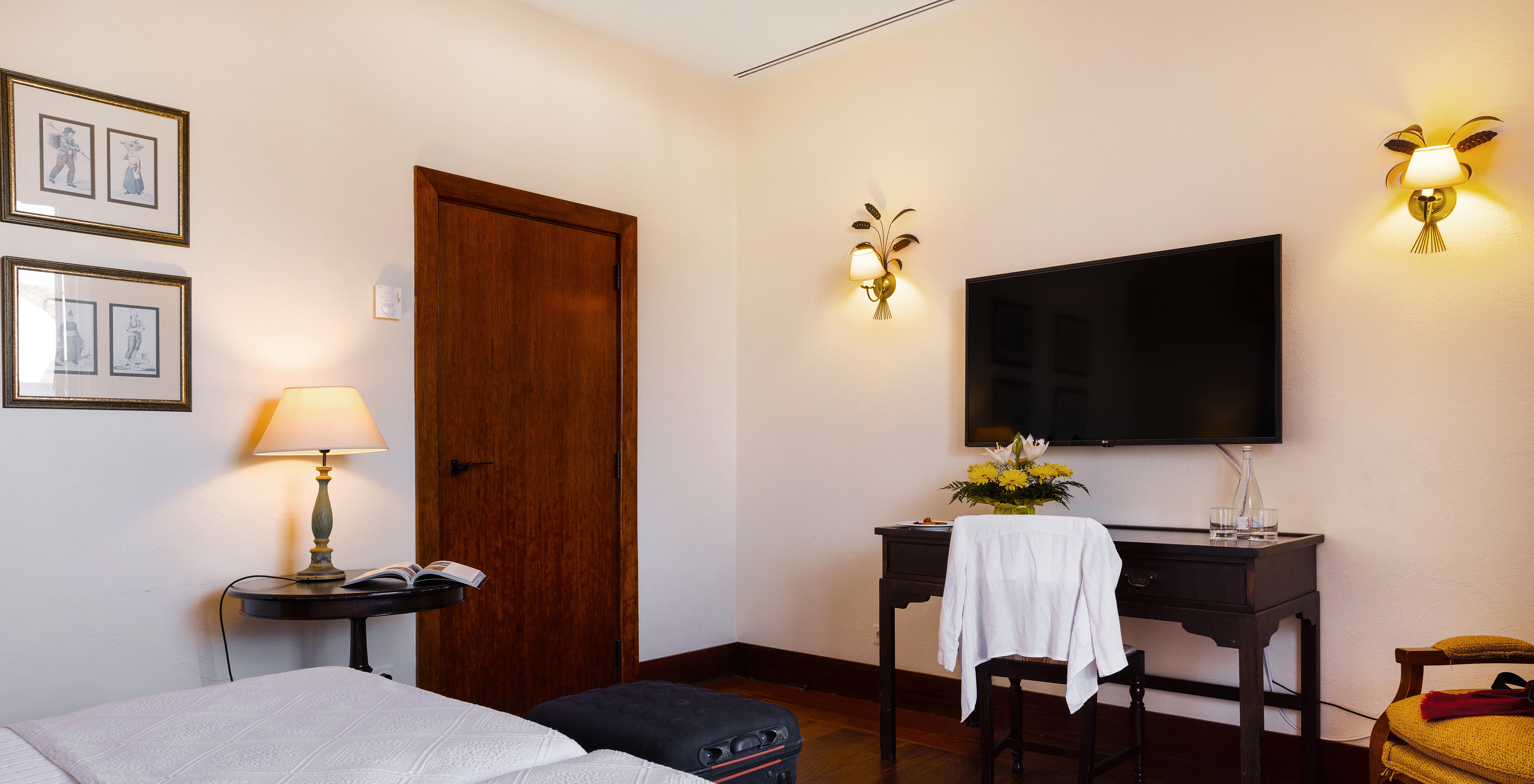 The Classic Room of The Pousada Convento Vila Viçosa has a door, two paintings, and a television in front of the beds