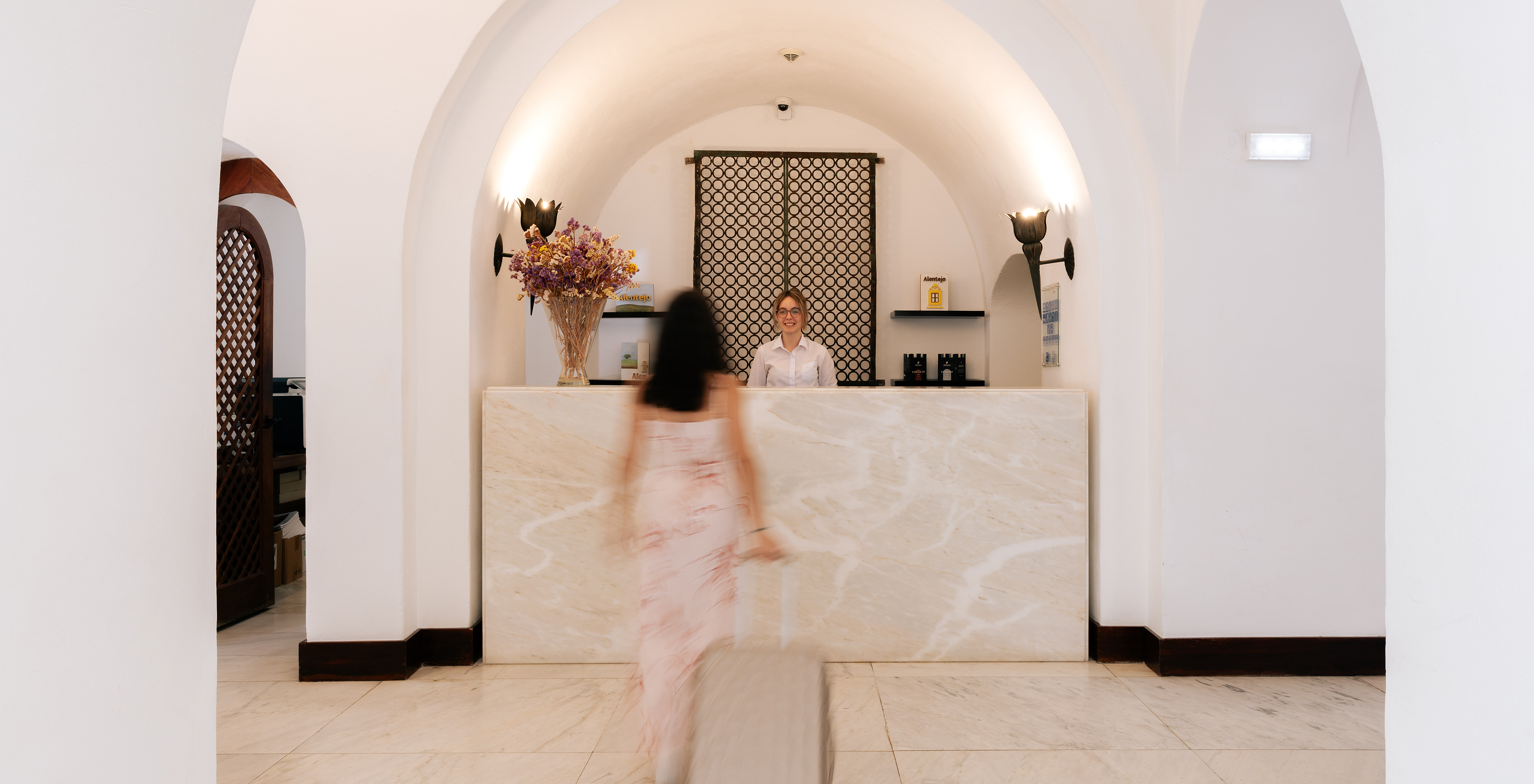 Reception of Pousada Convento Vila Viçosa, a hotel in the historic center, with a customer approaching the Pestana staff