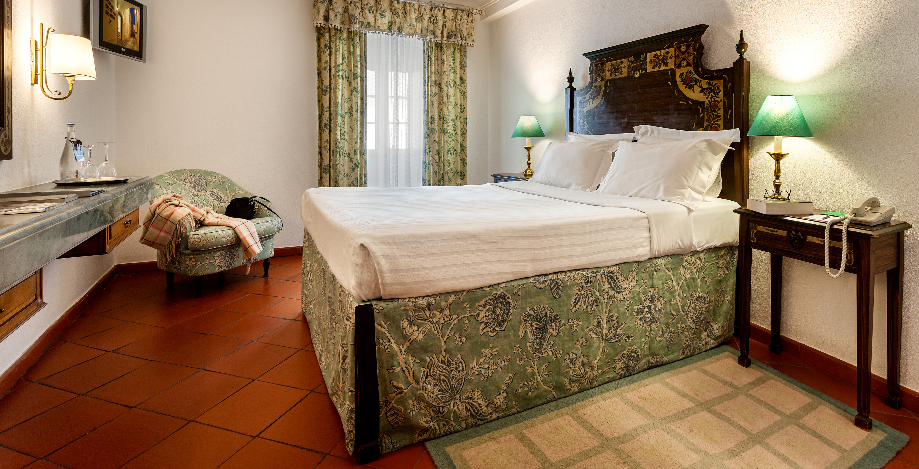 The Classic Room of The Pousada Marvão features a bed with a floral pattern and a dark wood headboard