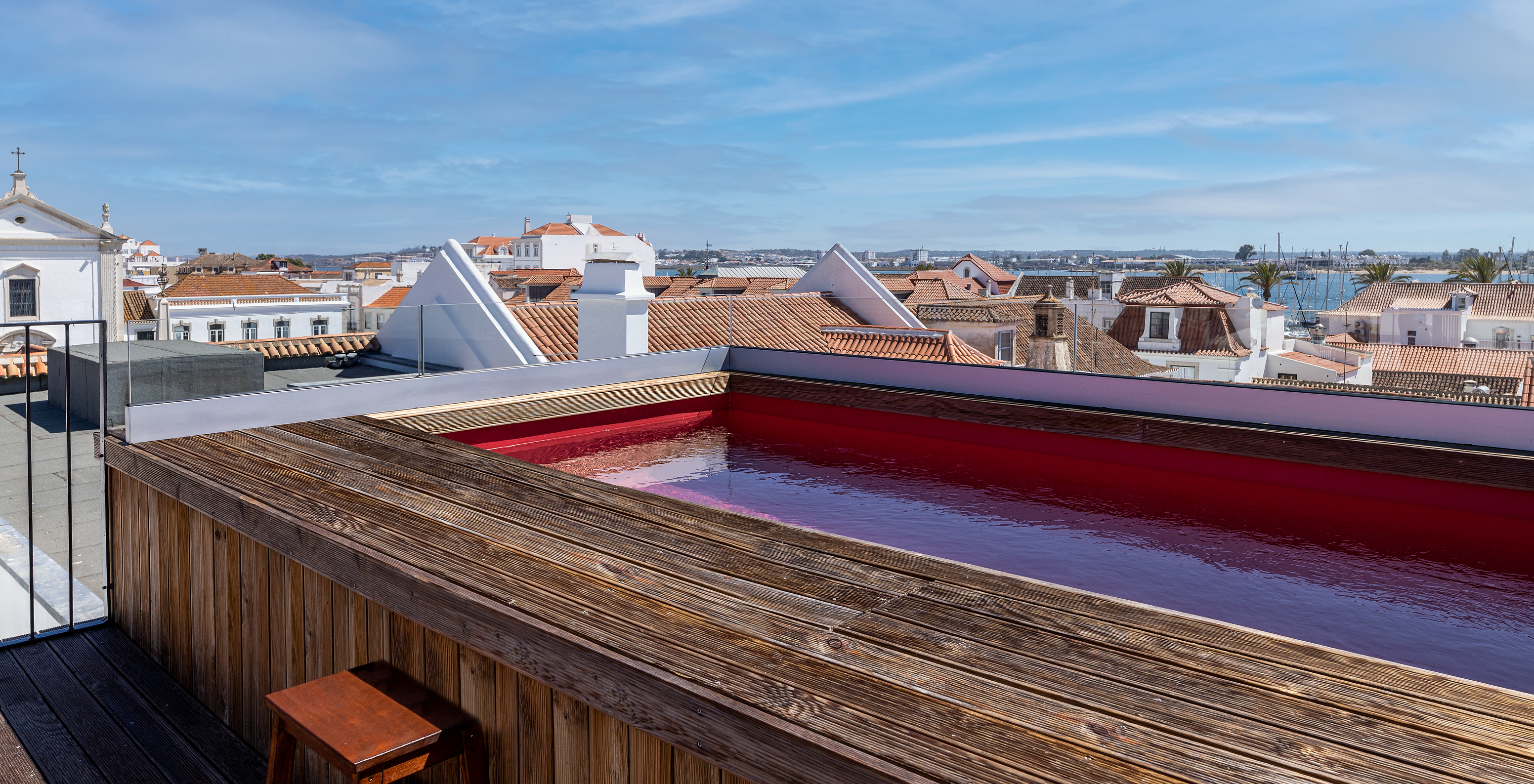 Small rooftop pool surrounded by wooden decking and city views at Historic Hotel Near Beach