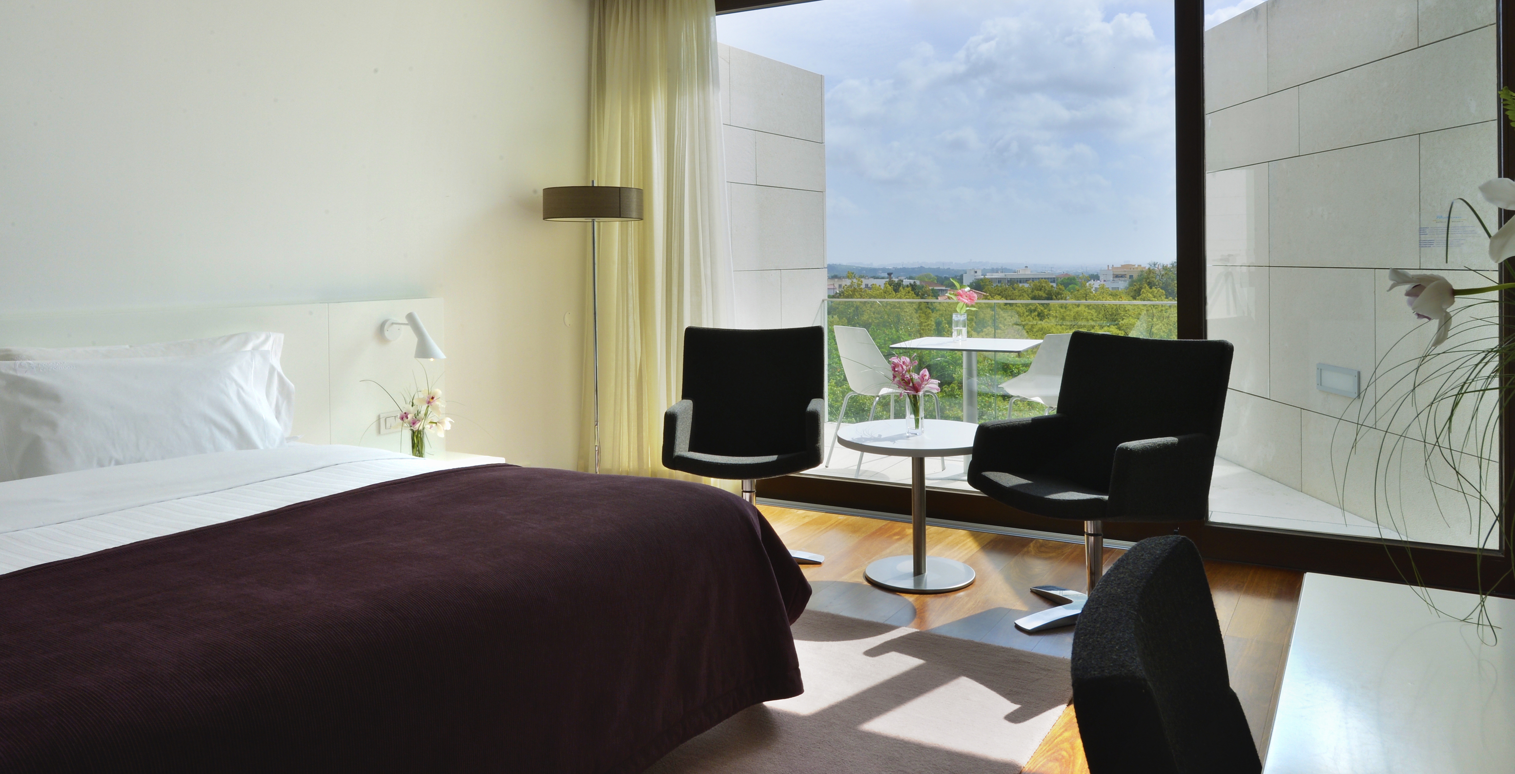 The Superior Room of The Pousada Palácio Estoi features a bed, a table with two chairs, and a window with balcony access