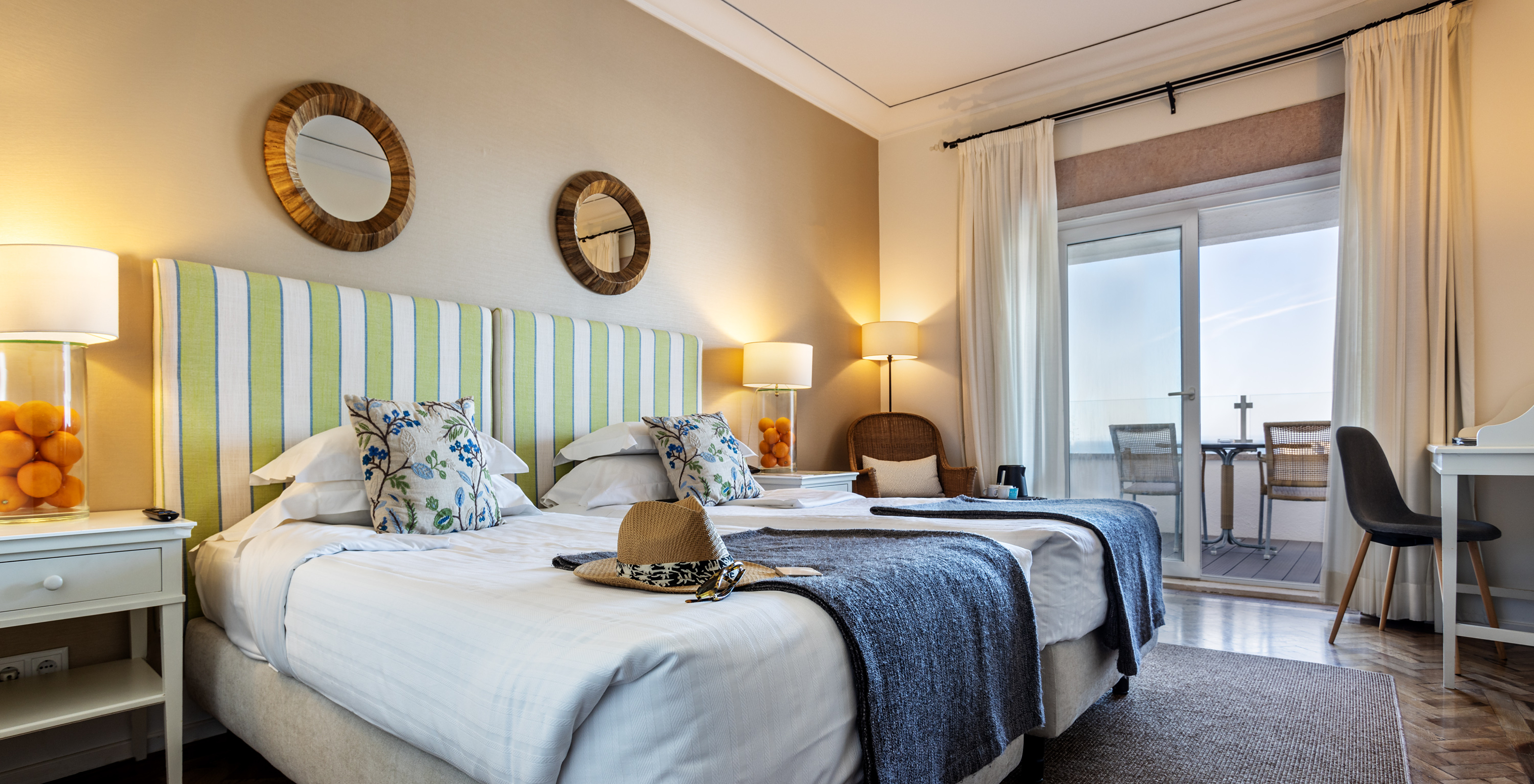 The Superior Sea View Room of Pousada Sagres has two beds with striped headboards, two round mirrors, and a balcony