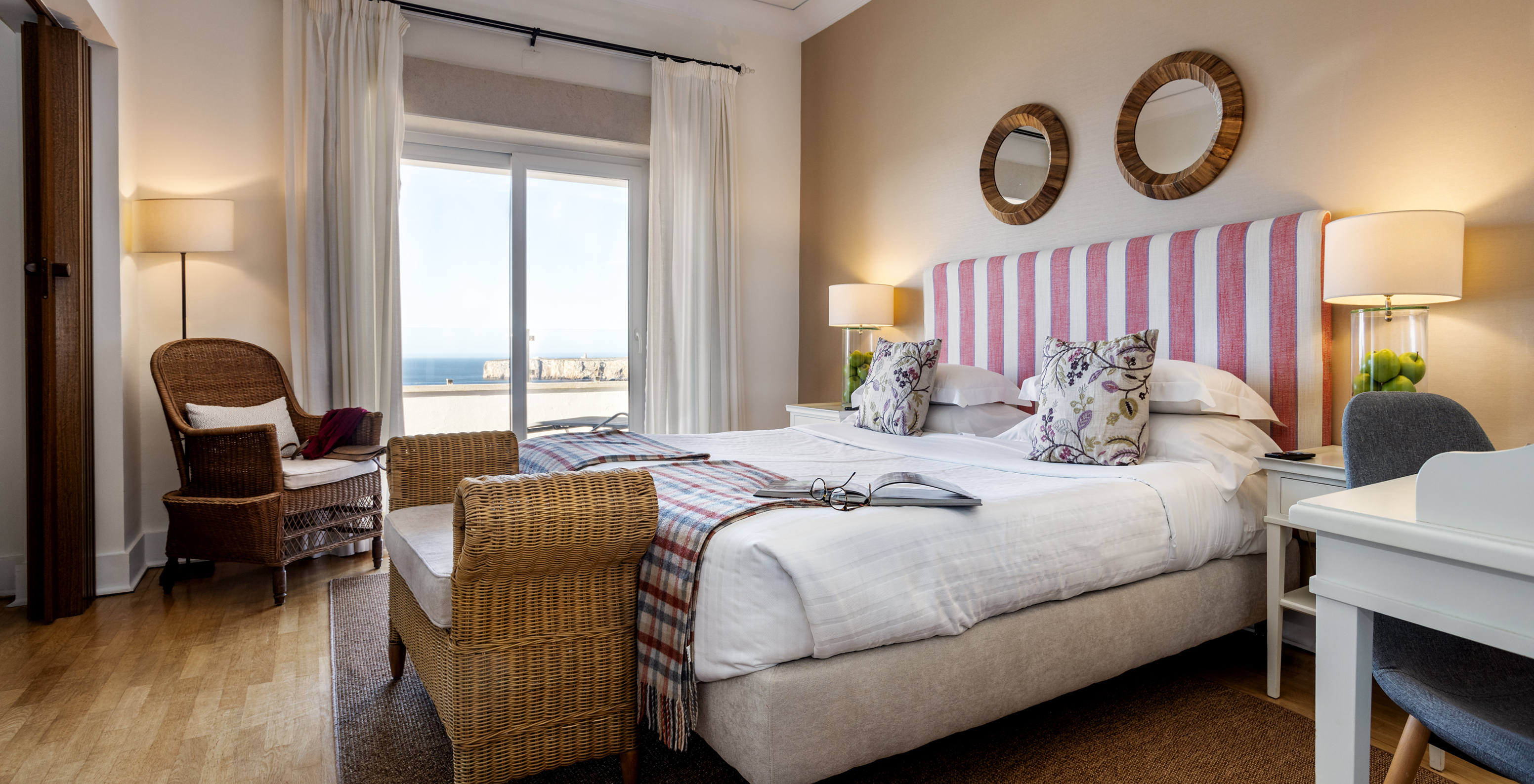 The Master Suite of Pousada Sagres has two beds with striped headboards, two round mirrors, and a balcony