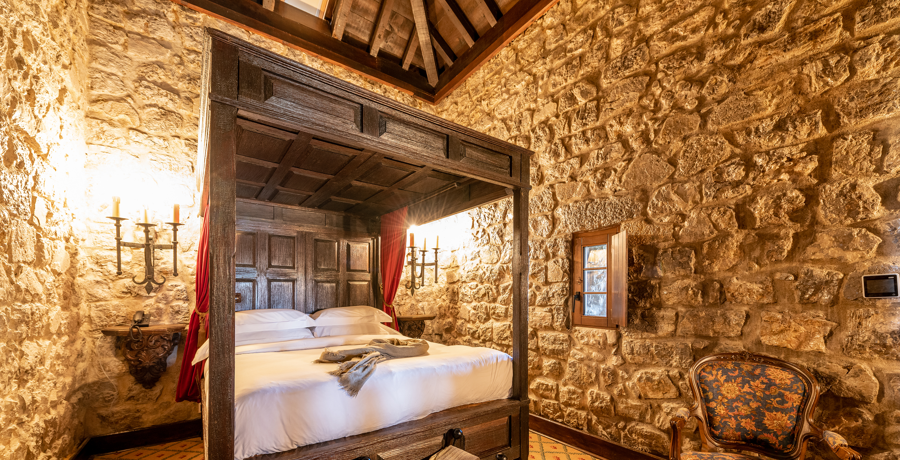 The Special Suite at Pousada Castelo Óbidos has a double bed with a medieval style bedside table