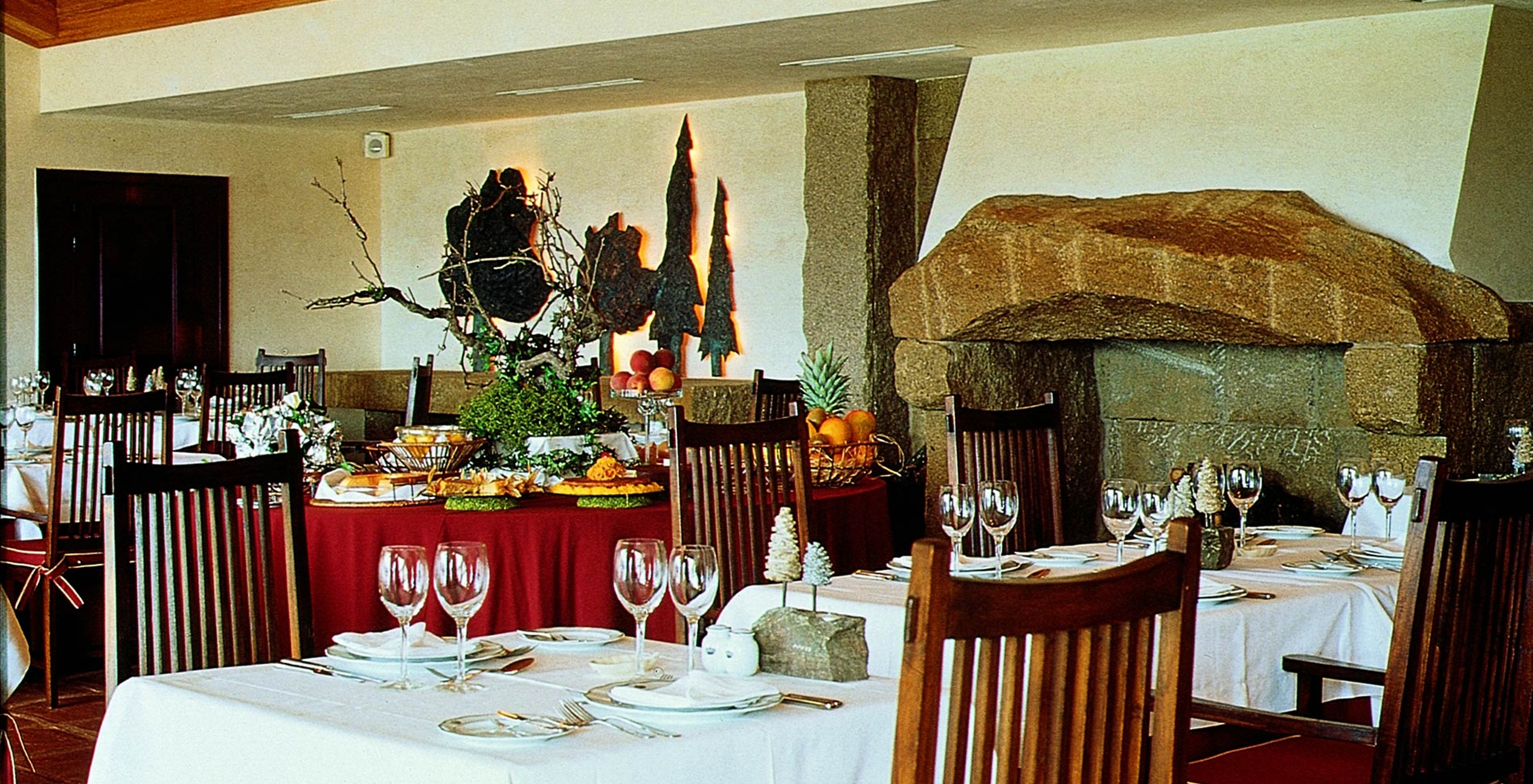 Restaurant of Pousada Convento Belmonte, with tables set for meals and a buffet with pastries and fruit