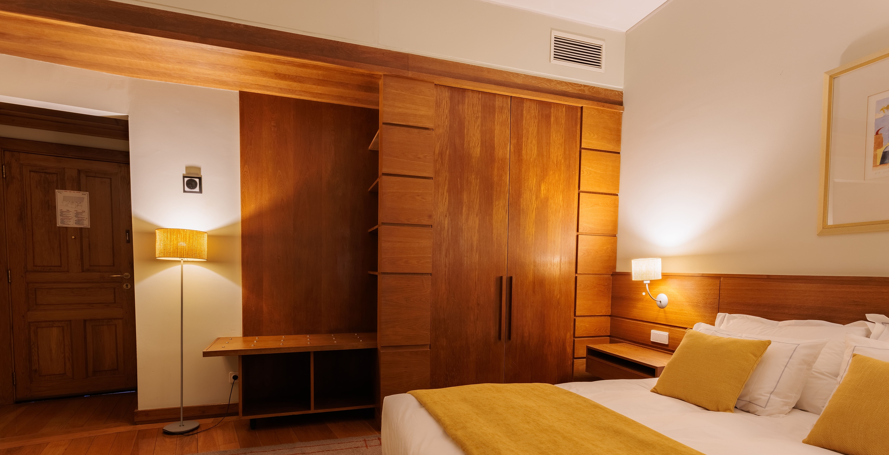 The Single Room of The Pousada Ourém features a double bed with a yellow bedspread and a wardrobe beside it