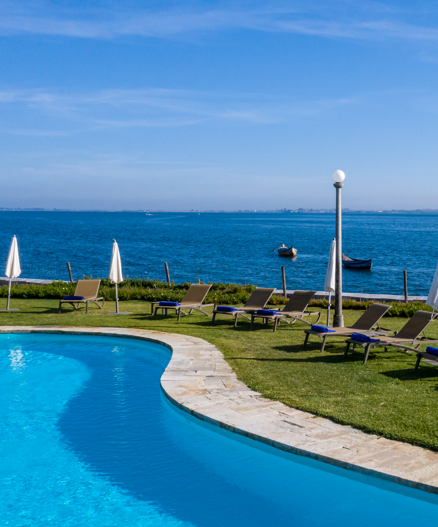 View of the outdoor pool at a charming hotel in Aveiro, with panoramic views of the lagoon