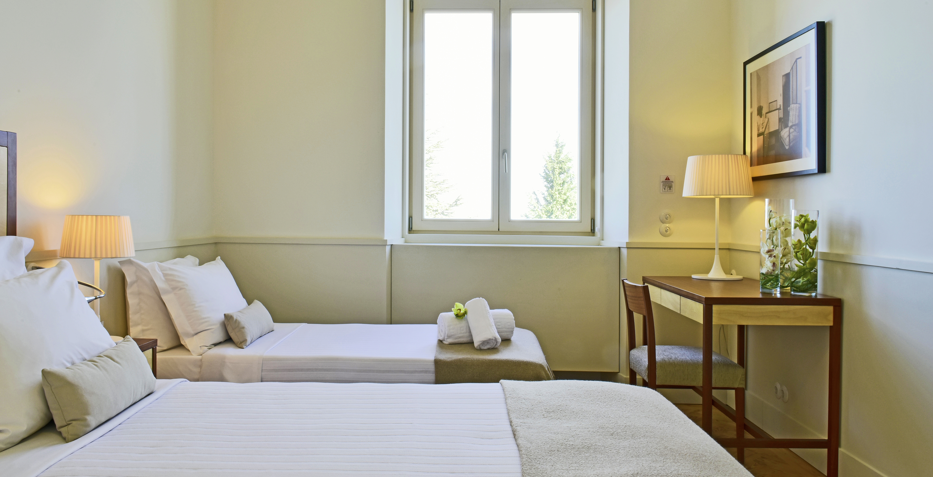 The Classic Room of The Serra da Estrela Inn has two beds, a desk with a chair, and a window