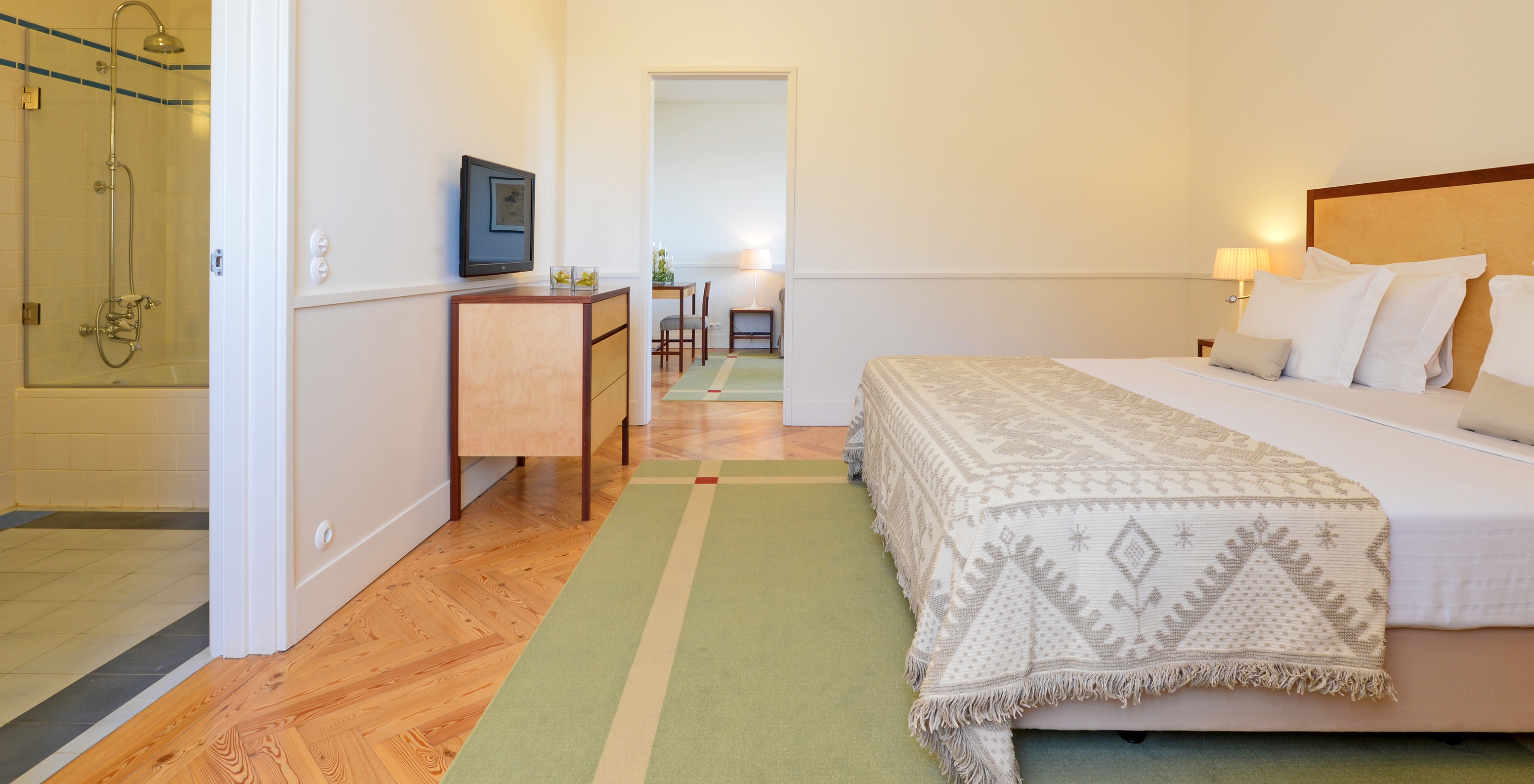 The Standard Suite of The Serra da Estrela Inn has a bedroom with a double bed, a wooden piece of furniture, and a TV