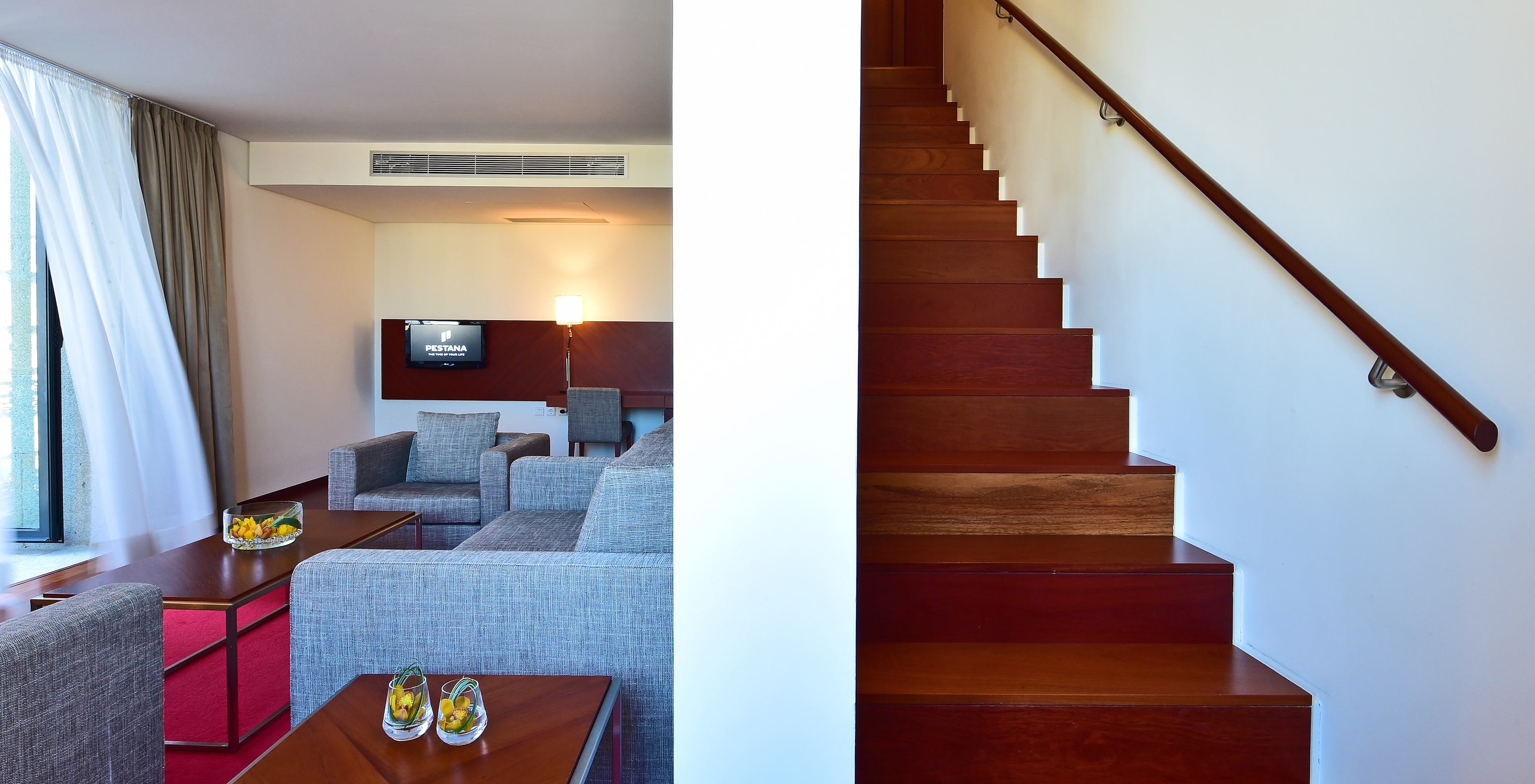 The Mezzanine Suite of the Pousada Viseu has two armchairs, a sofa, a desk, television and stairs to the mezzanine