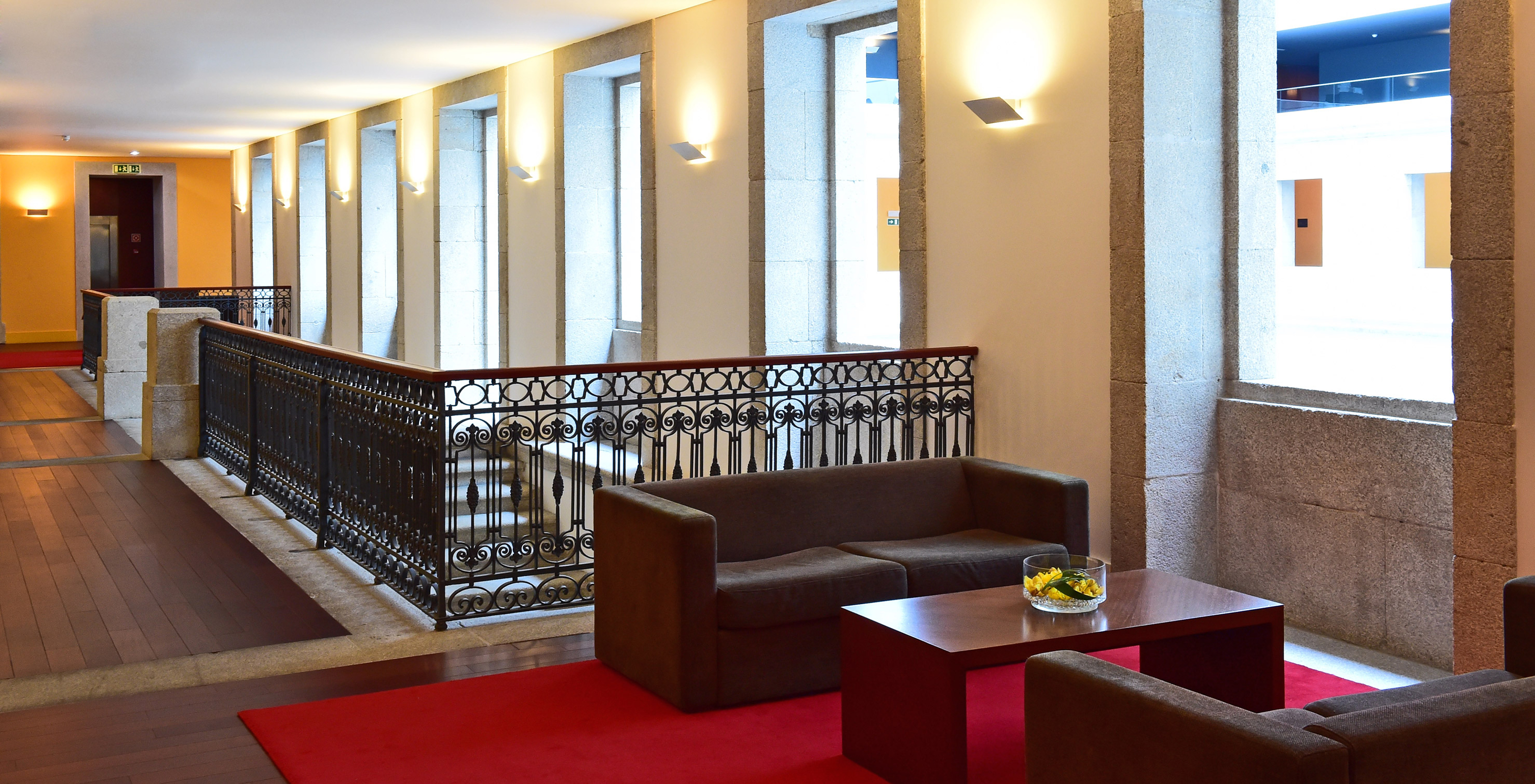 Hallway at Pousada Viseu, with wooden flooring, stone window frames, and two sofas with a coffee table