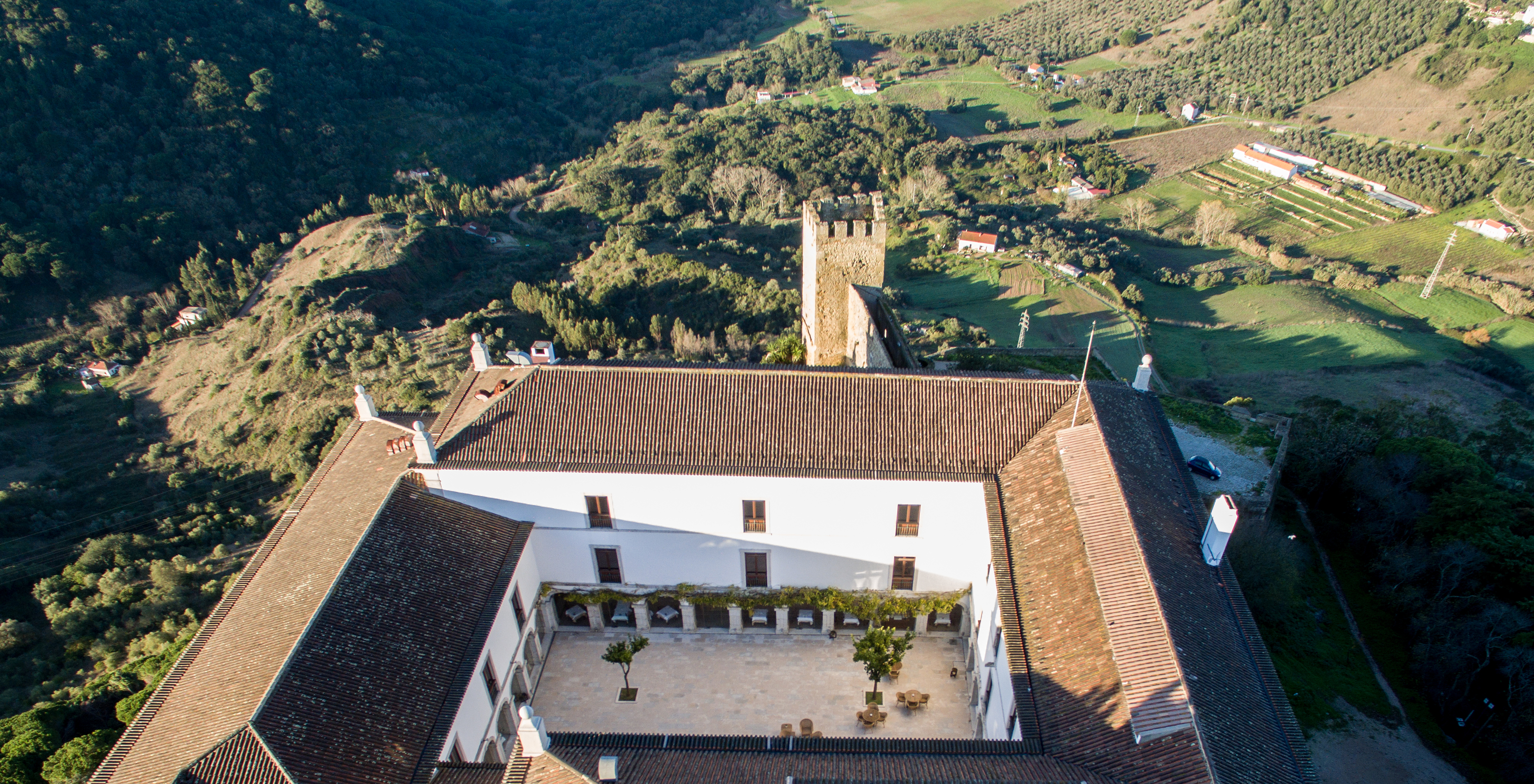 Aerial view of the cloister and surrounding region at Pousada Castelo Palmela, nestled in lush mountainous landscape