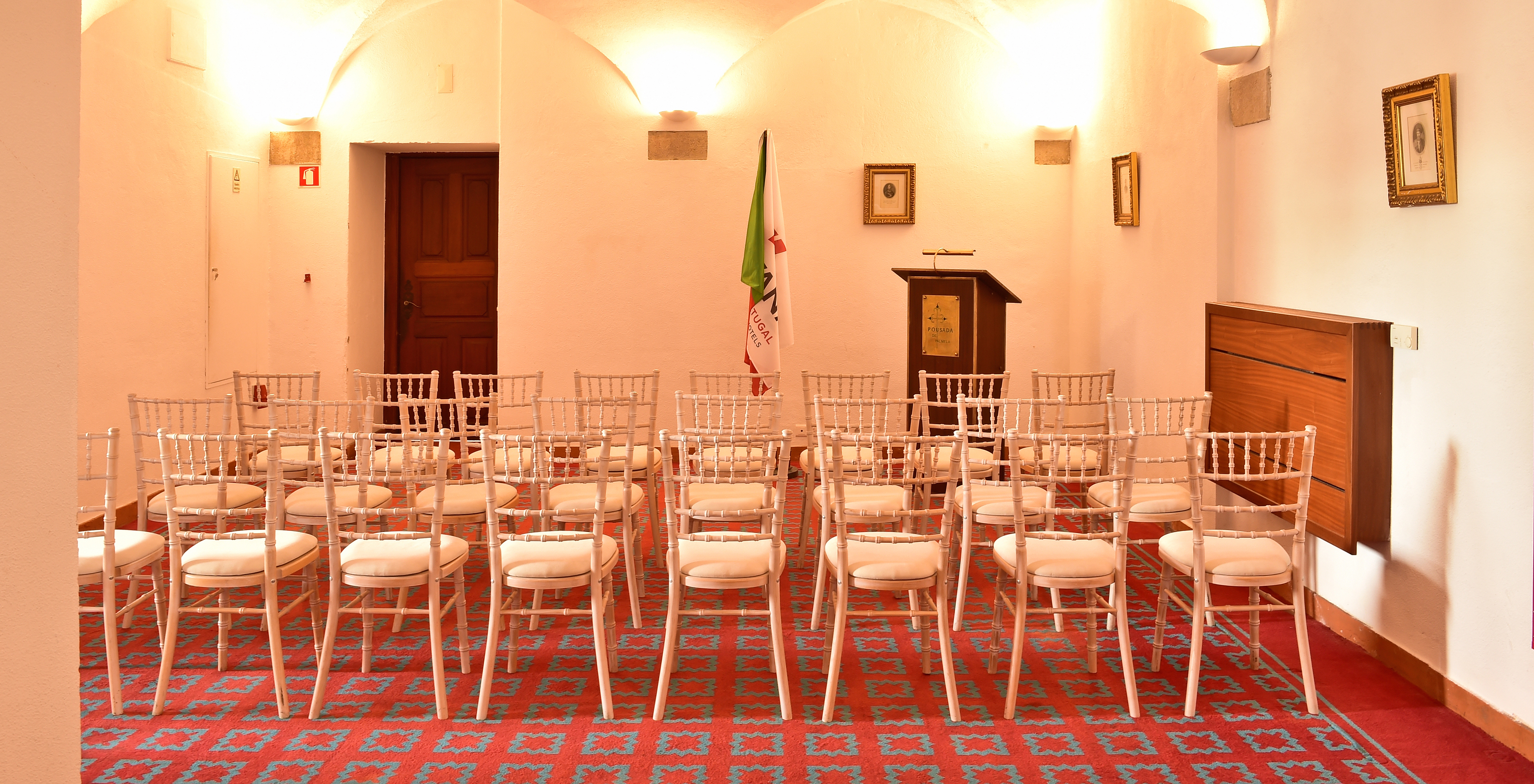 Meeting room at Pousada Castelo Palmela, hotel in Palmela, with several chairs, a flag, and a podium