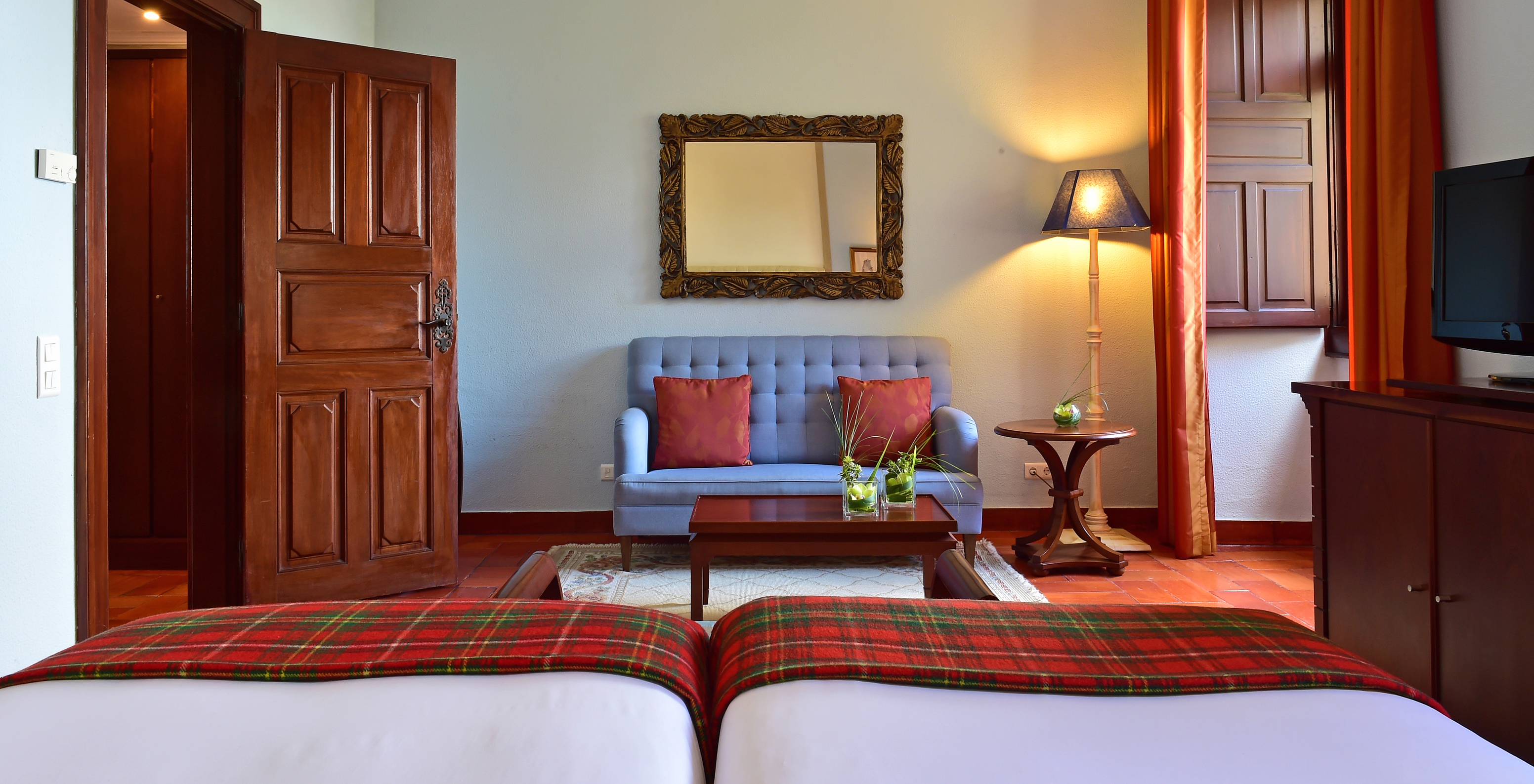 The Classic Family Room at Pousada Castelo Palmela has two beds, a blue sofa with a small table, and a window