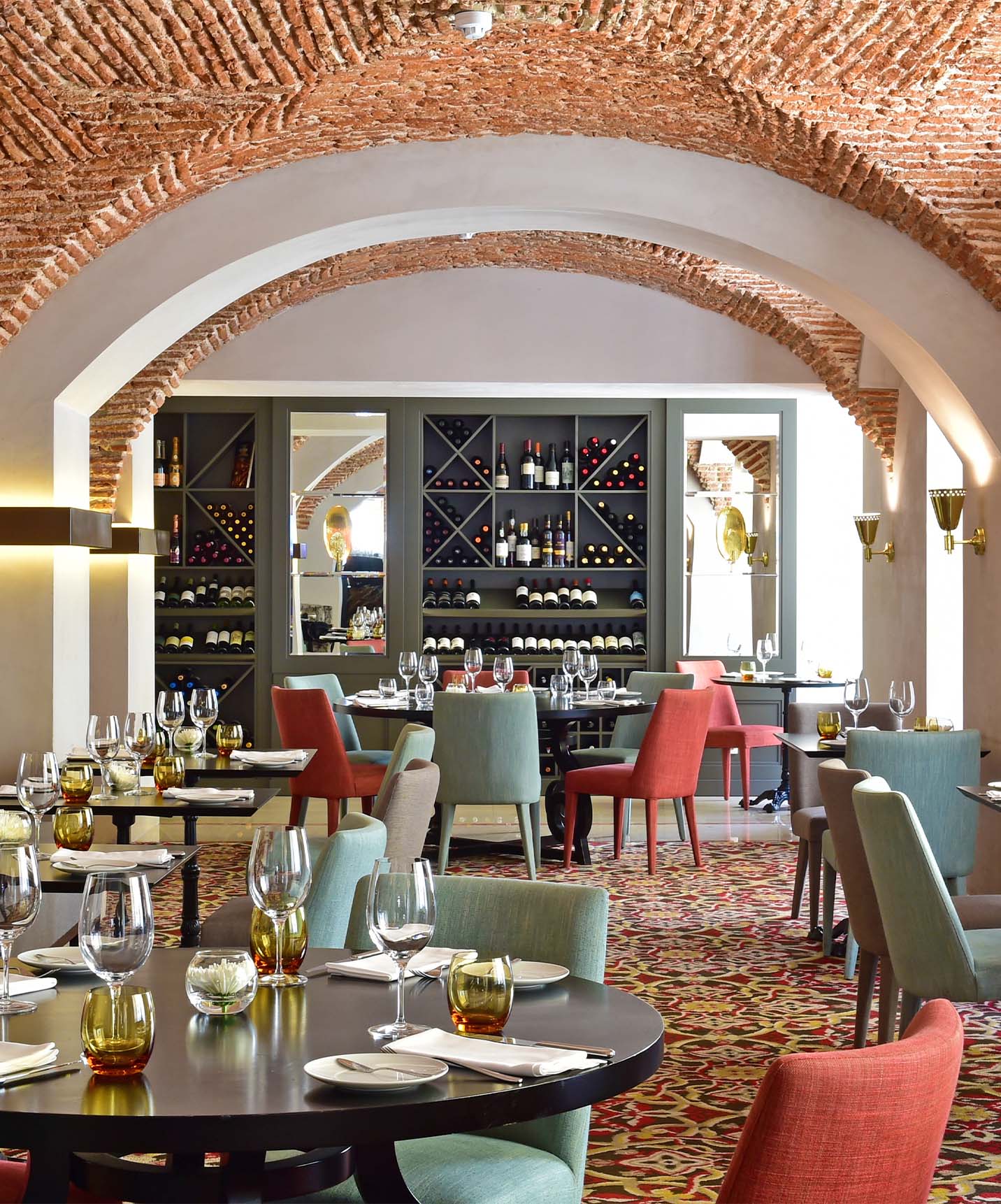 Restaurant of the historic hotel in downtown Lisbon, with round tables, cushioned chairs, and arched brick ceiling