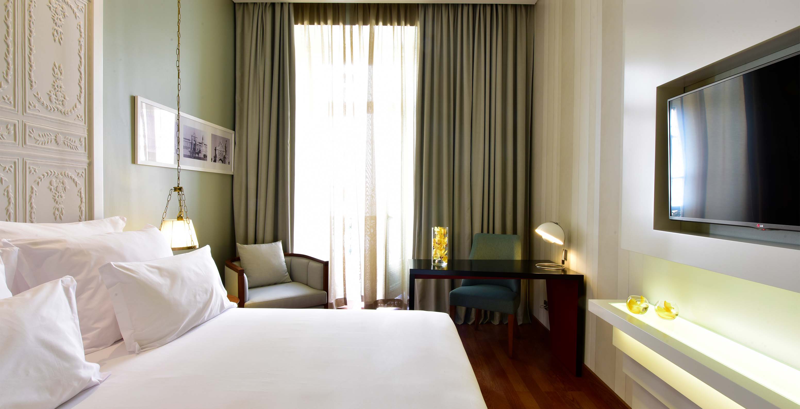 The Classic King Size Bed of The Pousada Lisboa Praça do Comércio has a double bed, a desk, and a large window