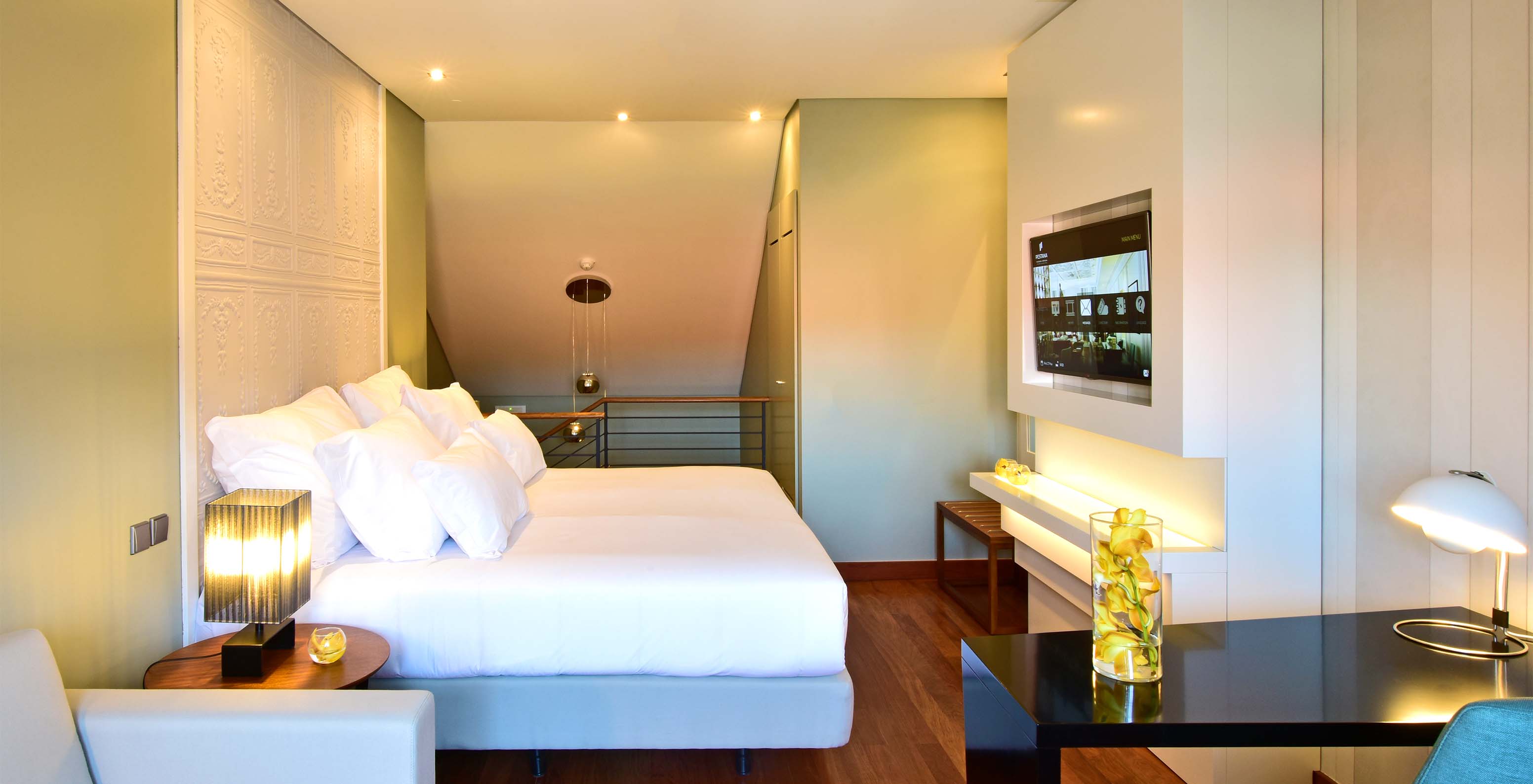 The Mezzanine King Size Bed of The Pousada Lisboa Praça do Comércio has a double bed, a television, a sofa, and a desk