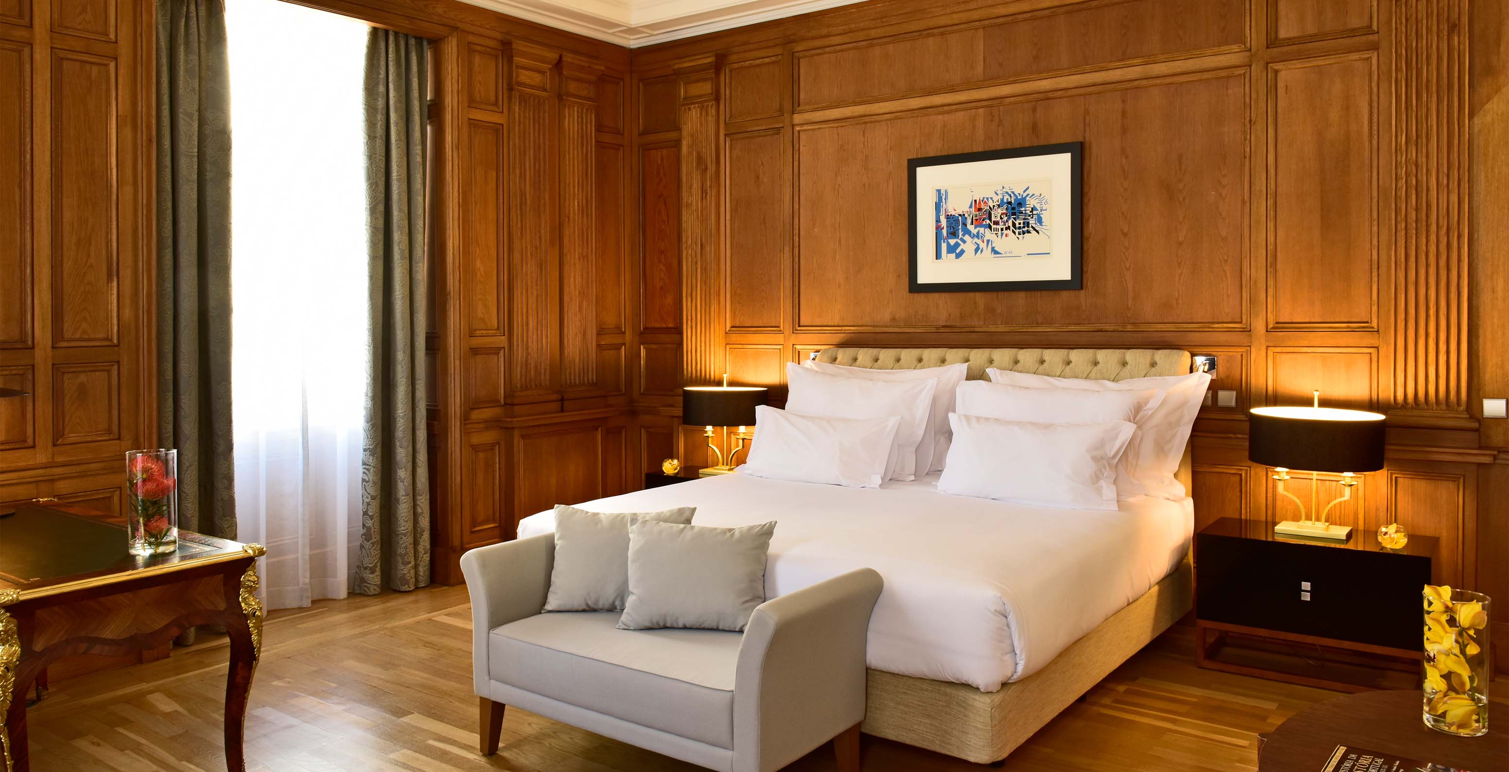 The Áurea Suite King Size Bed of The Pousada Lisboa Praça do Comércio has a double bed with a sofa at the foot and a window