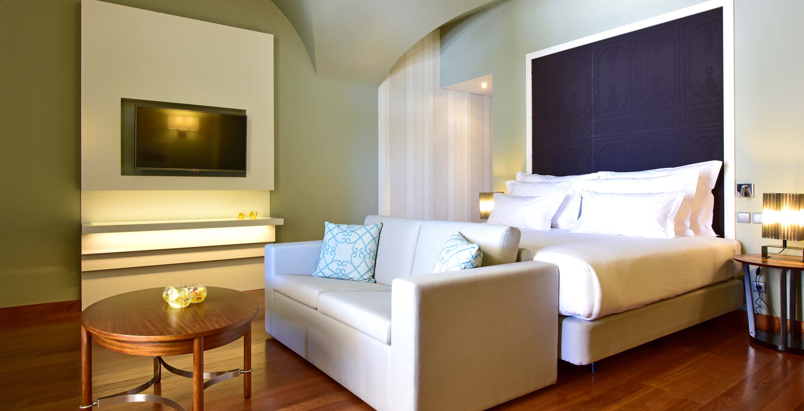 The Suite King Size Bed of The Pousada Lisboa Praça do Comércio has a double bed with a sofa at the foot and a television