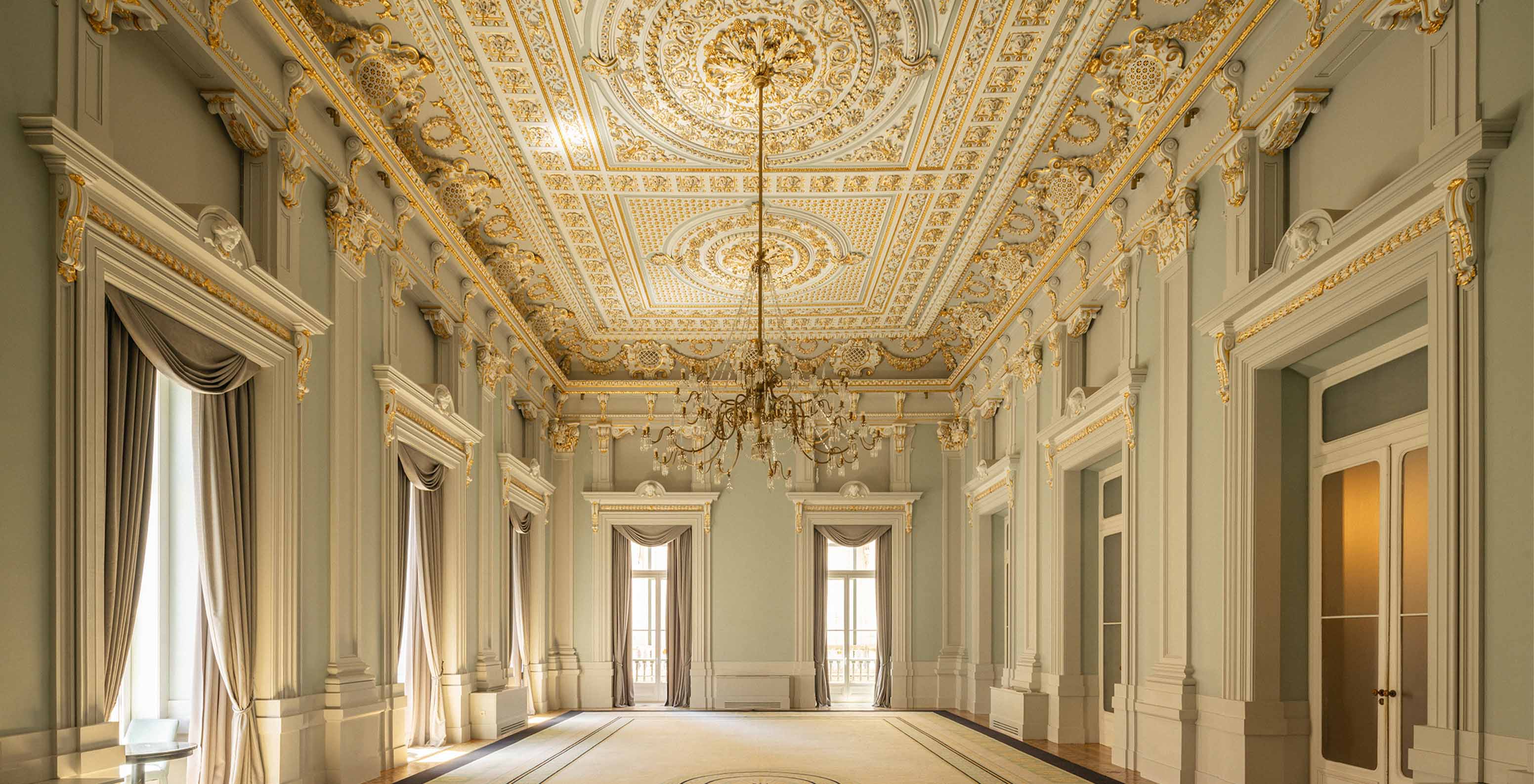 Imposing hall of the Pousada Lisboa Praça do Comércio with a decorated ceiling and carpet