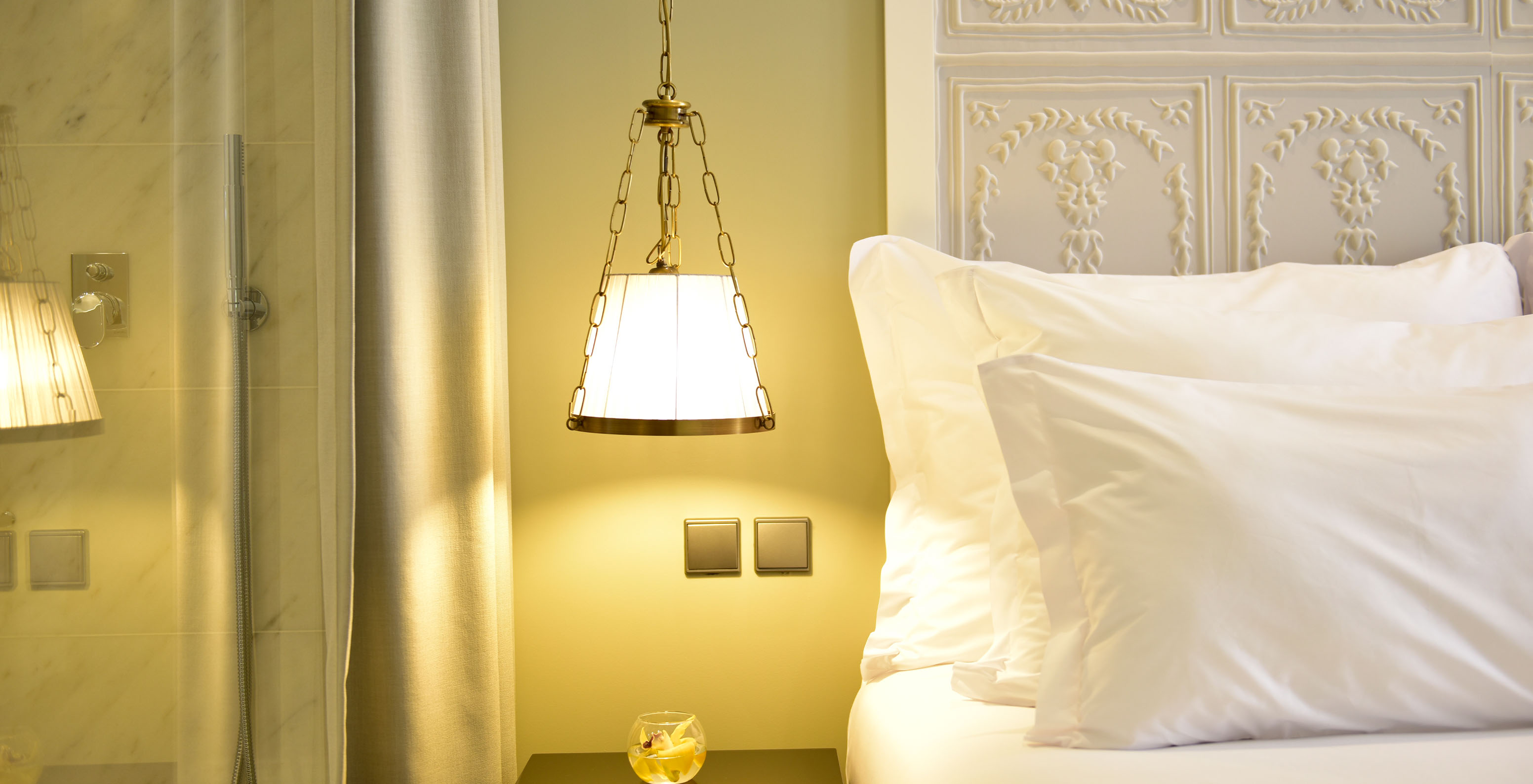 The Classic King Size Bed of The Pousada Lisboa Praça do Comércio has a lamp hanging over the bedside table