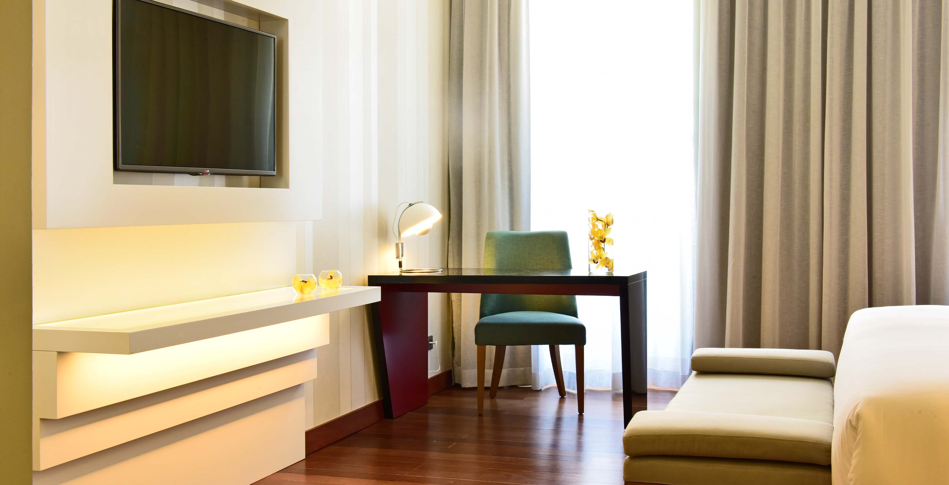 The Premium King Size Bed of The Pousada Lisboa Praça do Comércio has a desk with a padded chair and a television