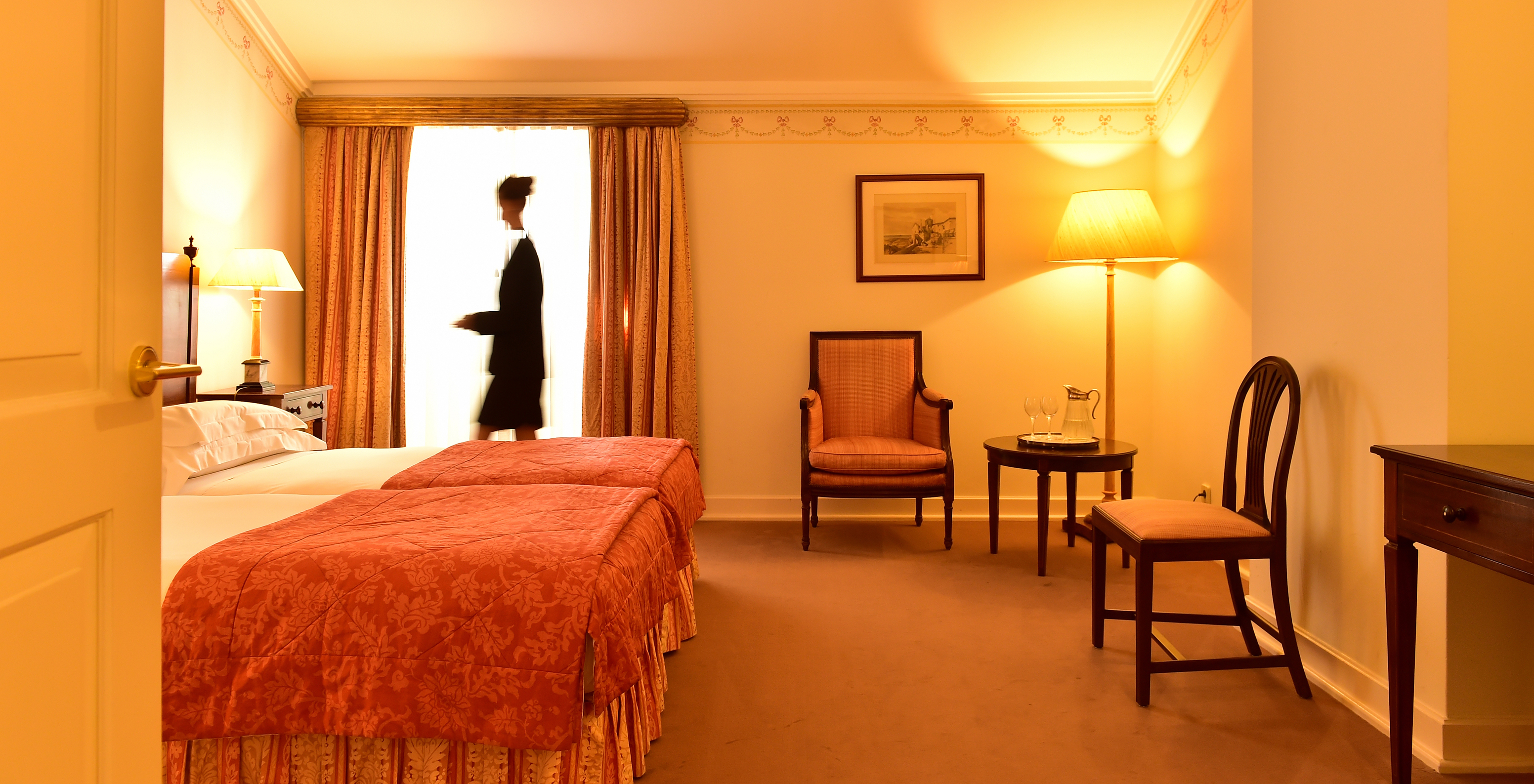 In The Classic Room of The Pousada Palácio Queluz a lady prepares the room for the upcoming guests