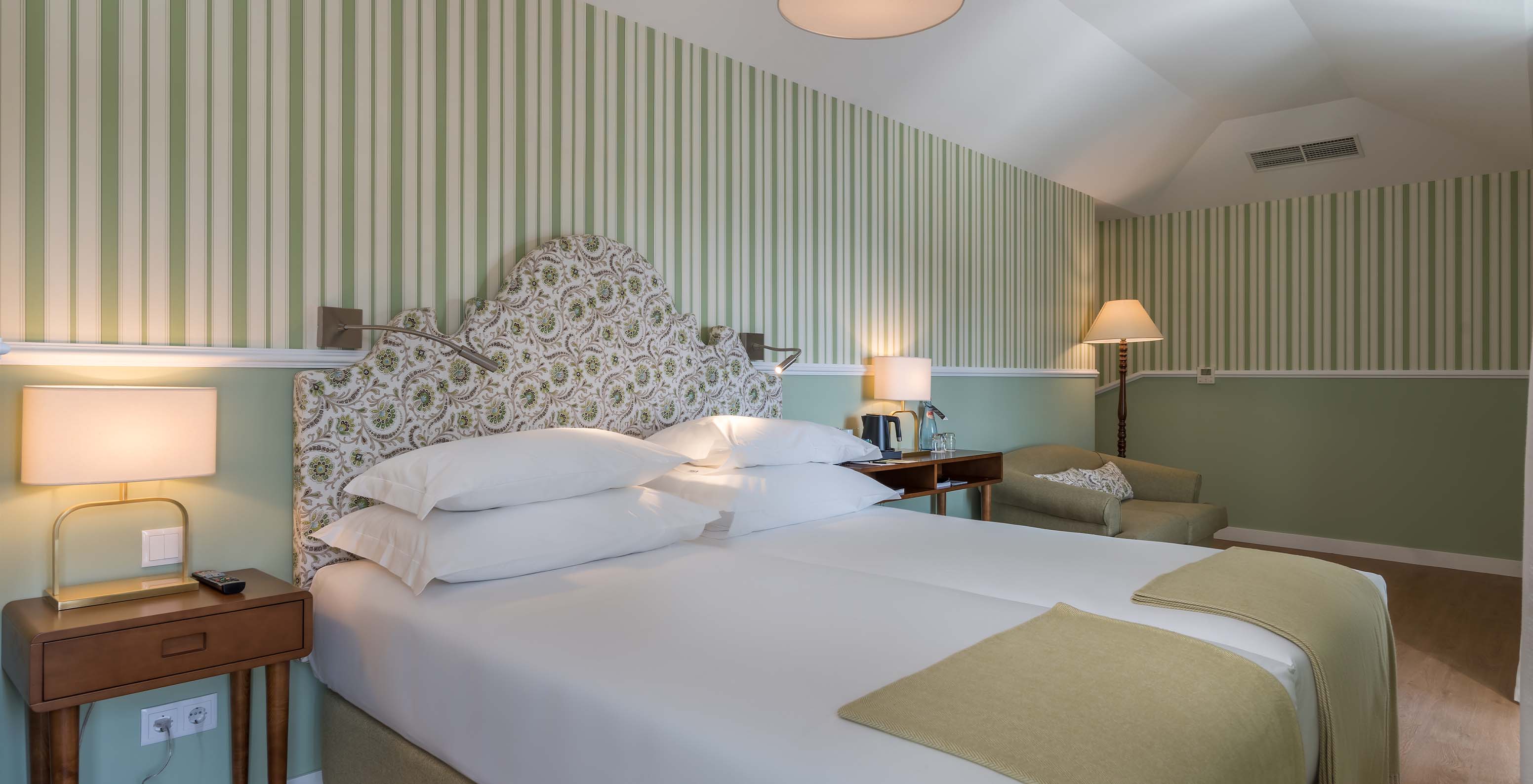 The Classic Room at Pestana Churchill Bay has a double bed, green striped wallpaper, and an armchair