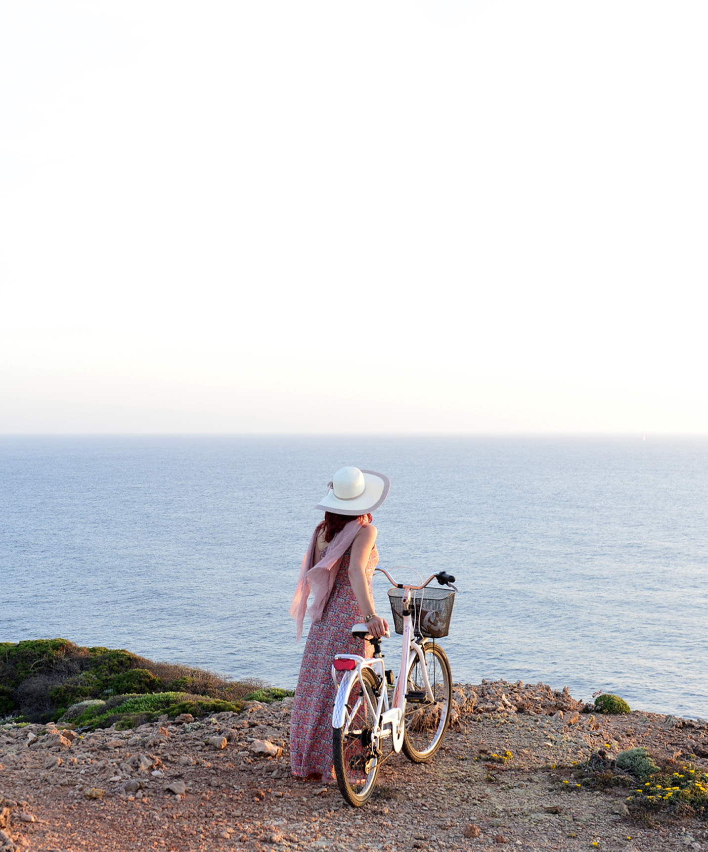 Woman walking with a bicycle in hand, along the cliffs on the Portuguese coast, provided by Pousadas de Portugal