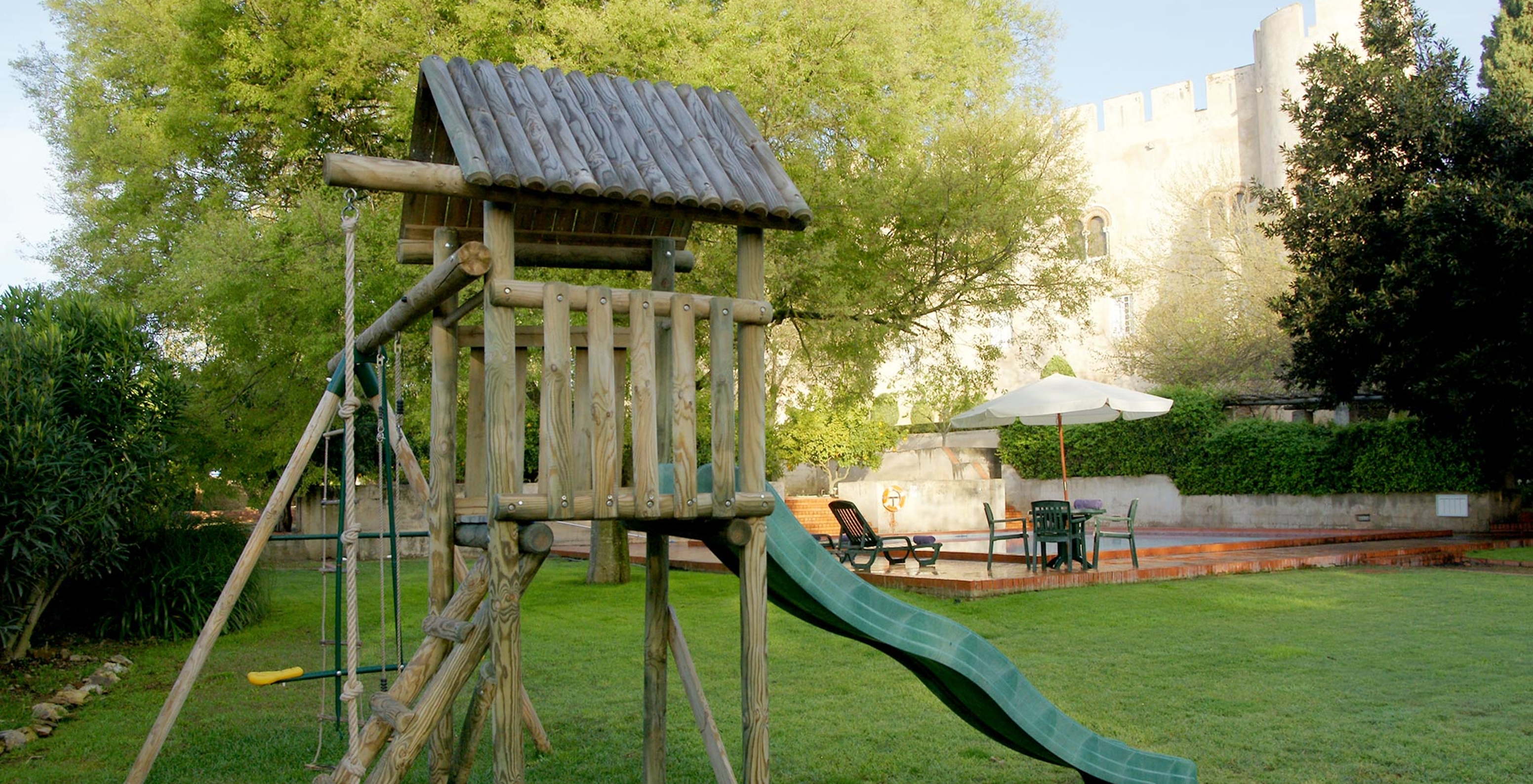 Parque infantil con un tobogán en la Pousada Castelo Alvito, con la piscina exterior al fondo