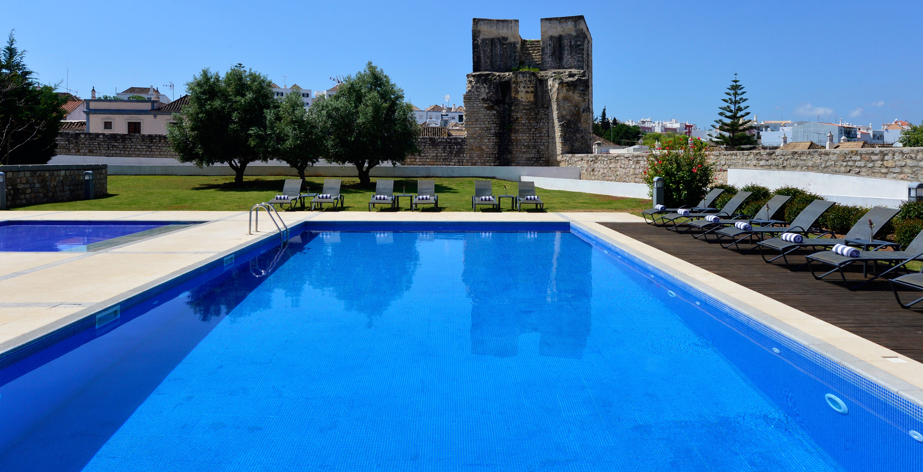 Piscina exterior para adultos y niños, con tumbonas y toallas en la Pousada Convento Tavira